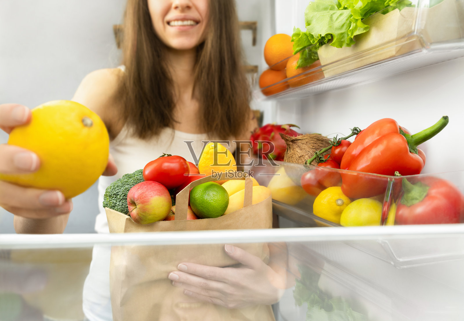 把购物袋里的东西放进冰箱的女人照片摄影图片