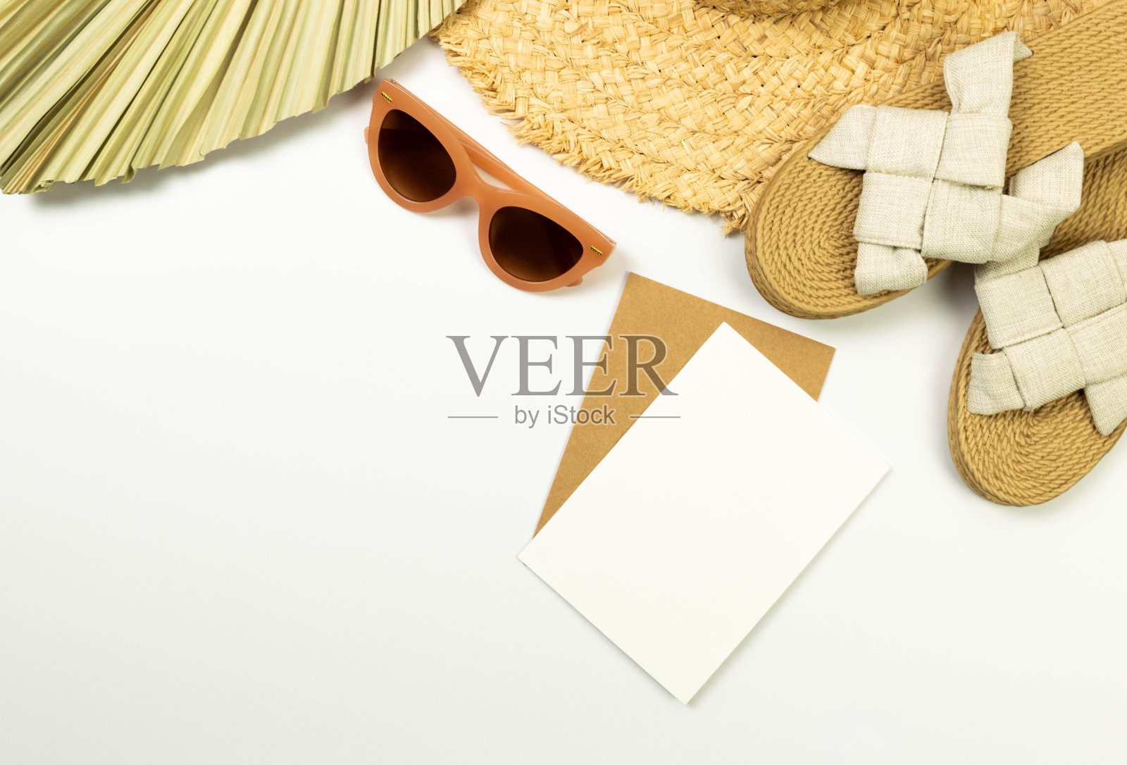 草帽、干棕榈叶、拖鞋、太阳镜和卡片在白色背景上的俯视图。夏季时尚、度假、沙滩壁纸。照片摄影图片