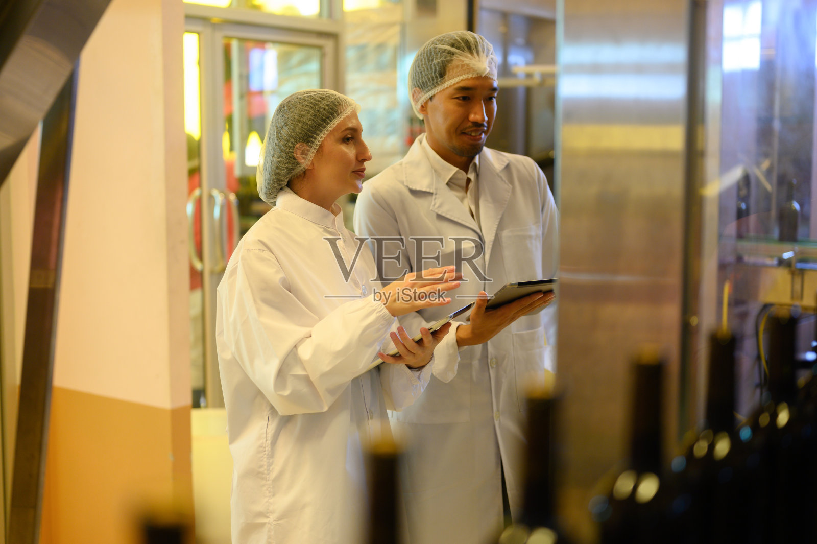 葡萄酒检查员在大型现代酒庄的饮料行业工作，并在酒庄仓库测试葡萄酒。照片摄影图片