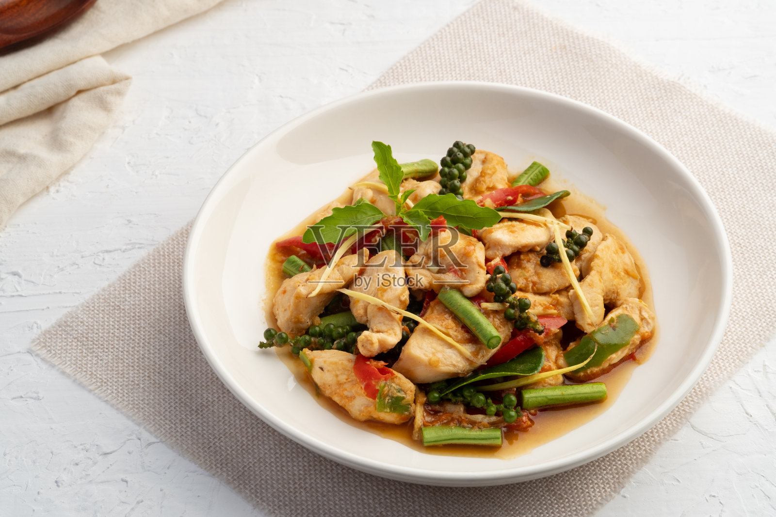 白盘辣味鸡胸肉配辣椒和鸡根。照片摄影图片