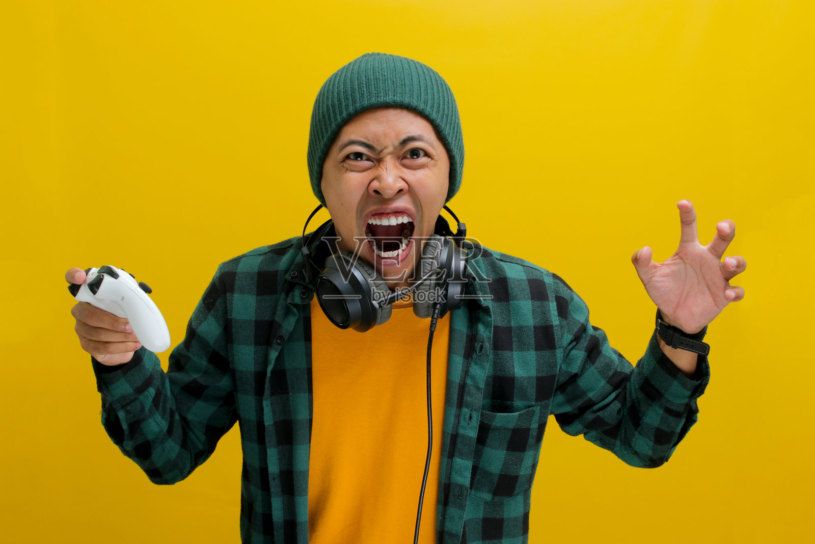 一名愤怒的亚洲年轻人在使用游戏机手柄玩电子游戏时显得很紧张照片摄影图片