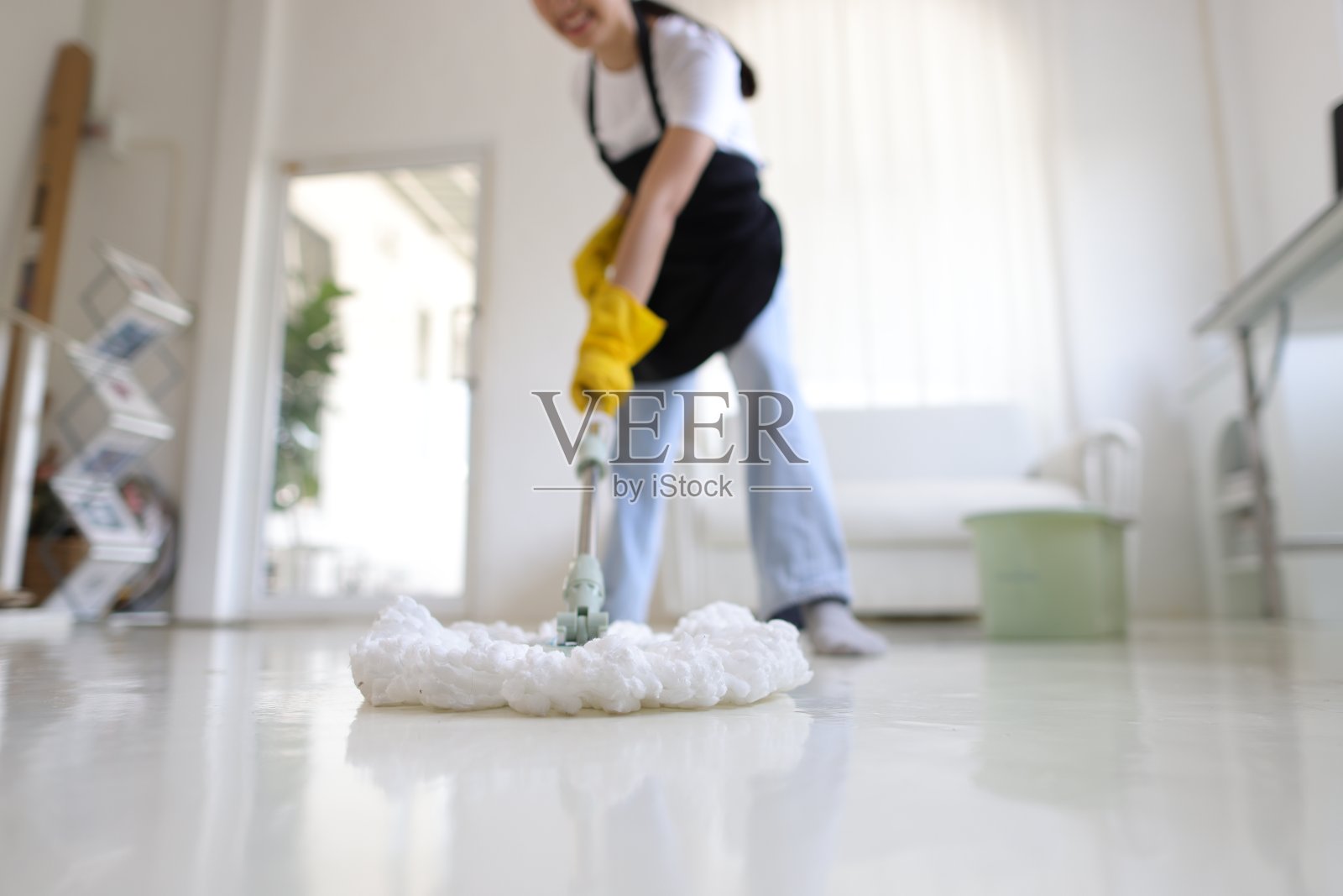 清洁工正在家里用拖把拖地。照片摄影图片