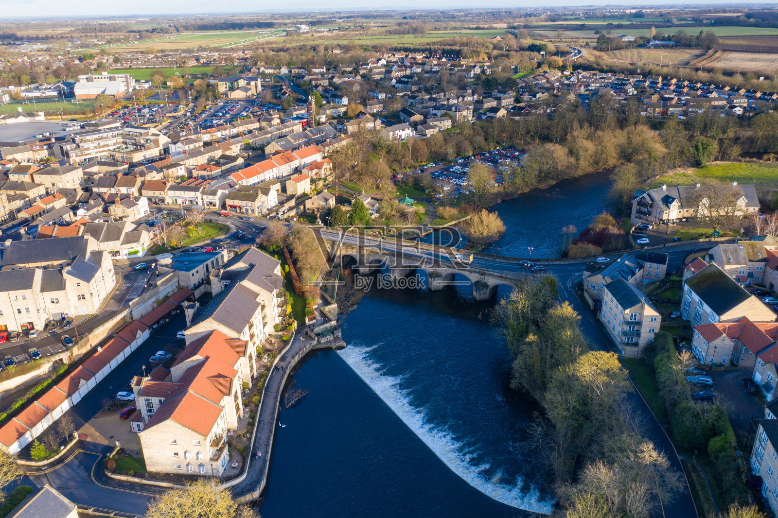 英国西约克郡韦瑟比镇中心的航拍照片，显示了沃夫河上的车辆驶过通往镇中心的小桥，拍摄于冬季。照片摄影图片