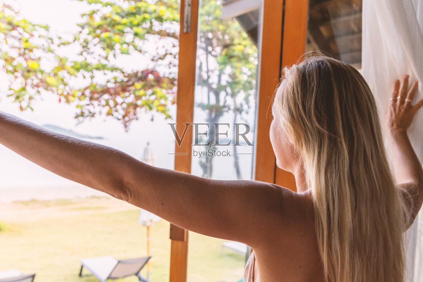 女人拉开窗帘迎接新的一天照片摄影图片