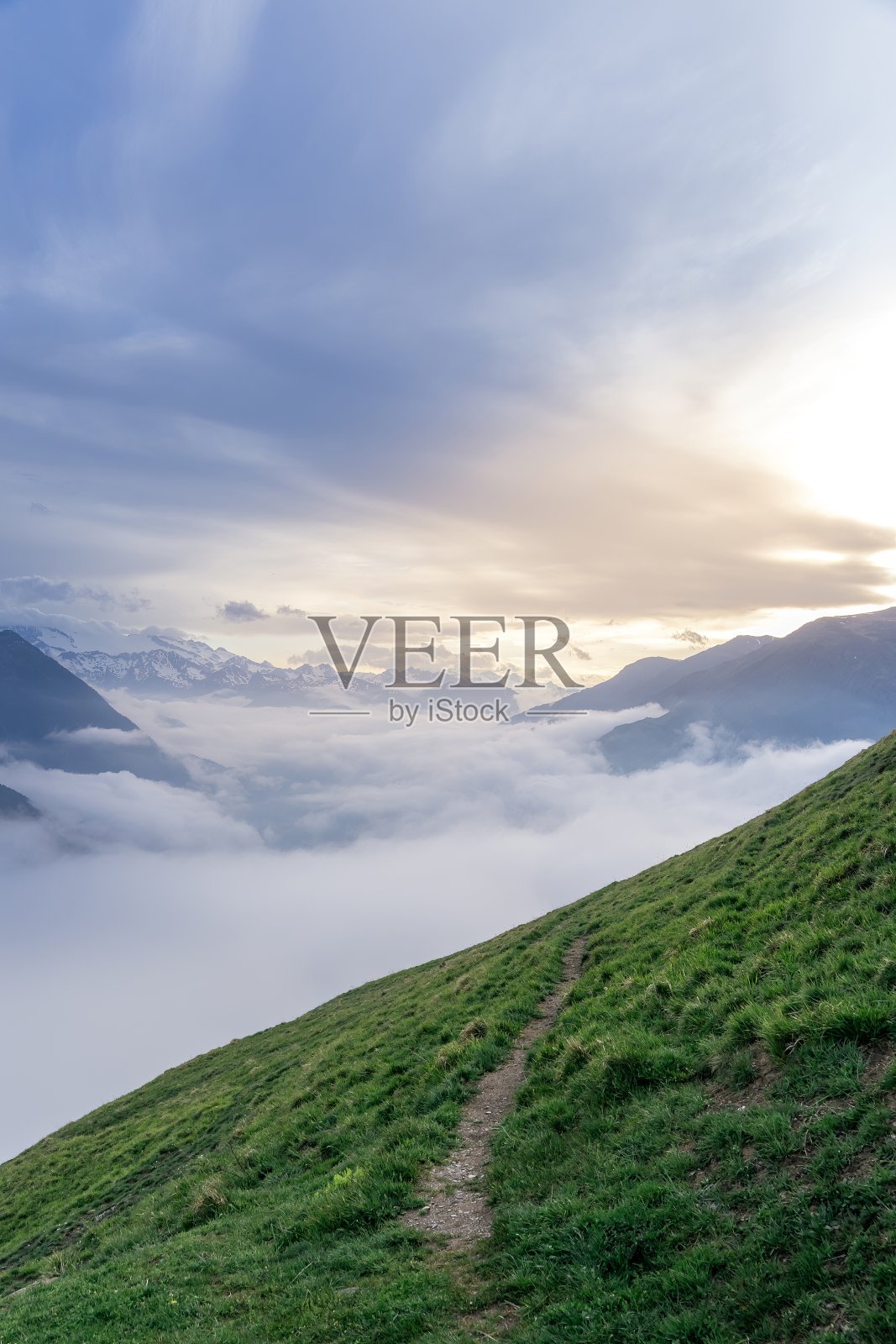 日落时分比利牛斯山下云海环抱的绿色山路。Vall d'Aran，西班牙加泰罗尼亚照片摄影图片