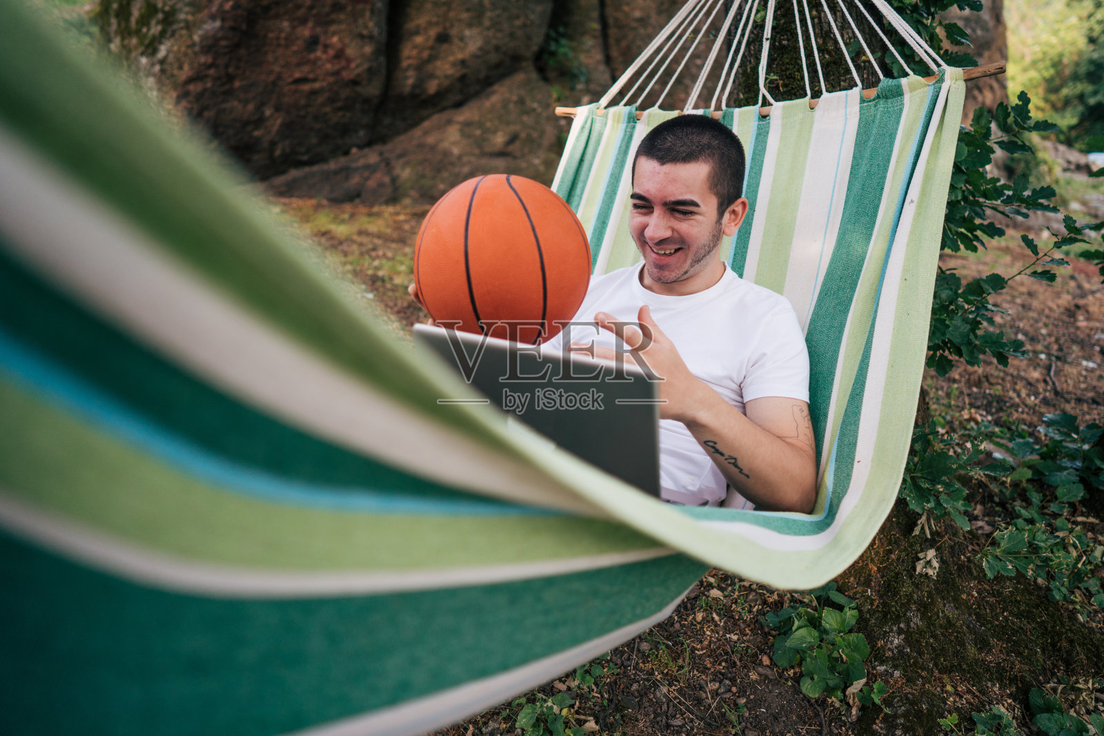 年轻人躺在电脑上看篮球比赛照片摄影图片