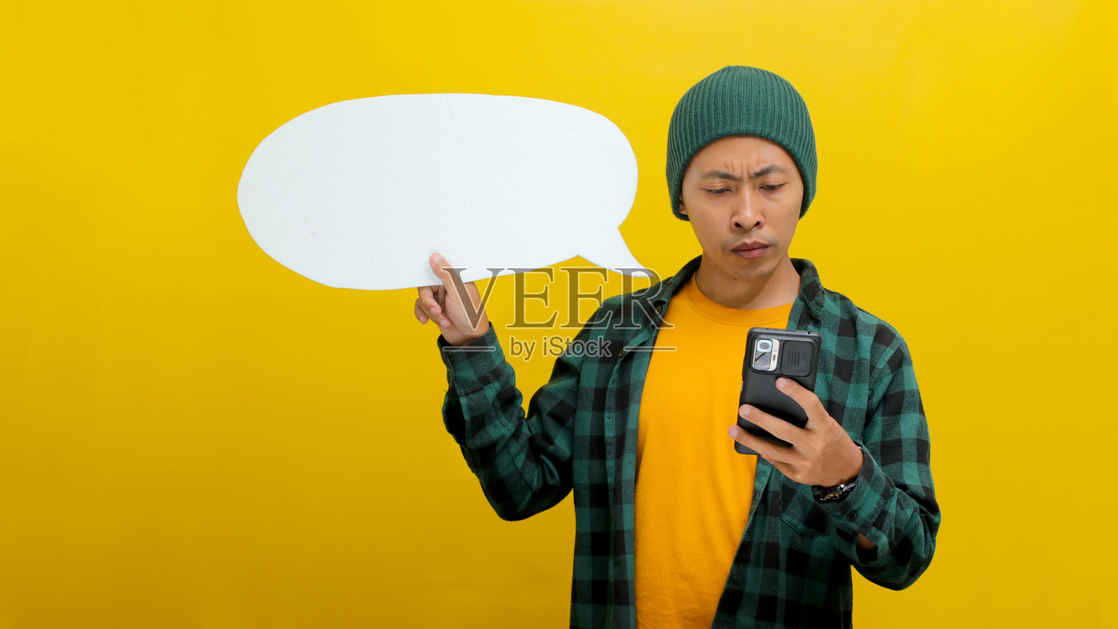 一名不满的亚洲男子拿着手机和语音泡泡在思考照片摄影图片