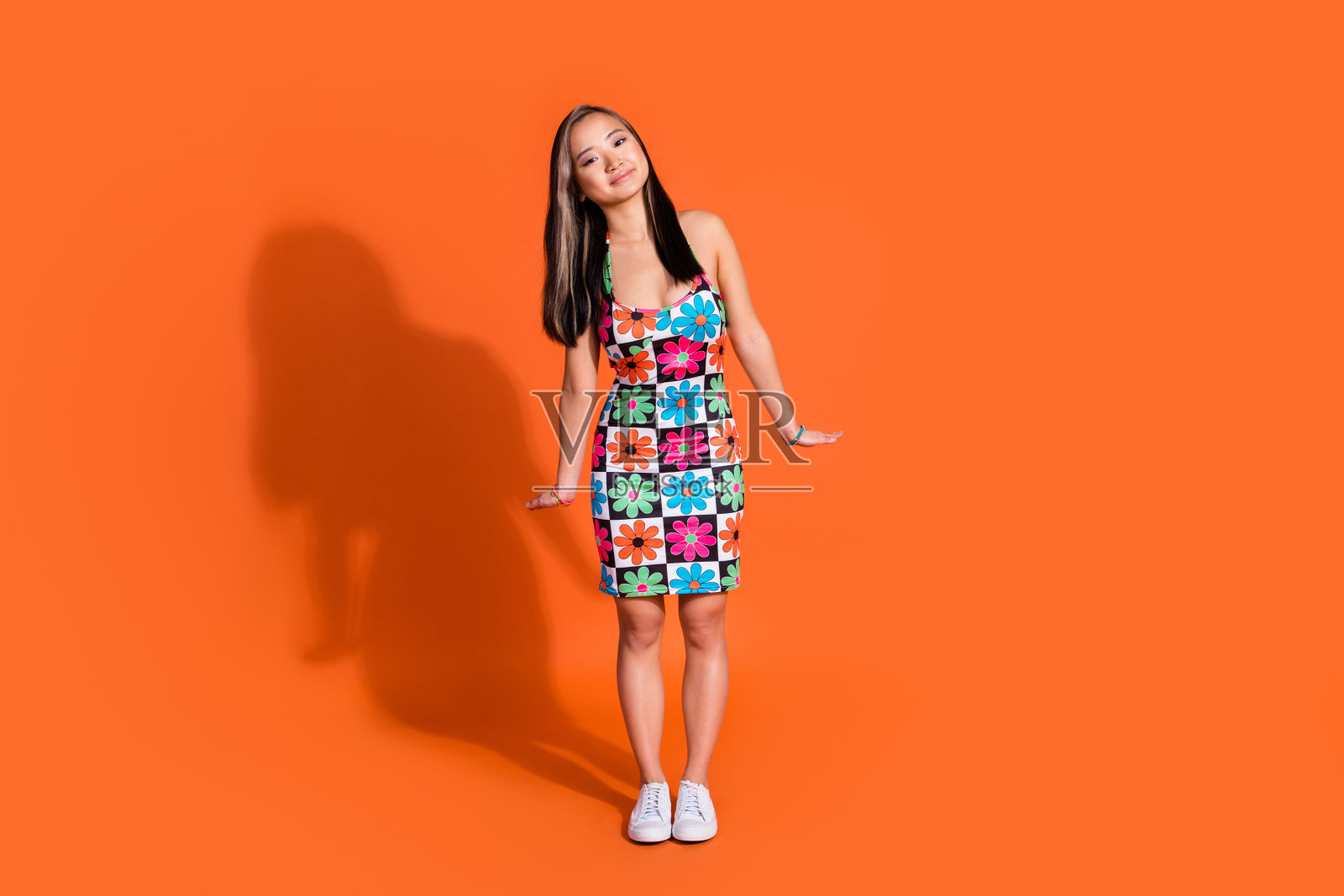 全尺寸照片的好心情的女人与染色的发型，穿着印花时尚的连衣裙站像洋娃娃孤立的橙色背景照片摄影图片