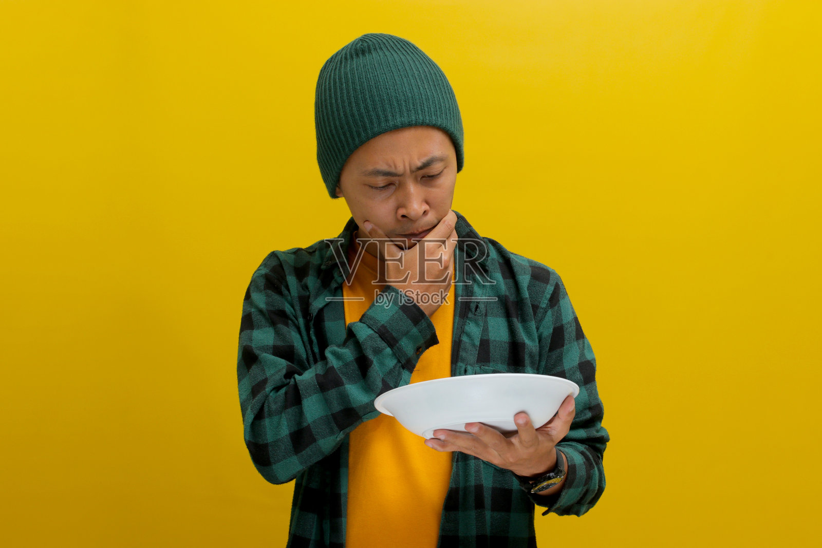 沉思的年轻亚洲男子拿着盘子在想该吃什么照片摄影图片