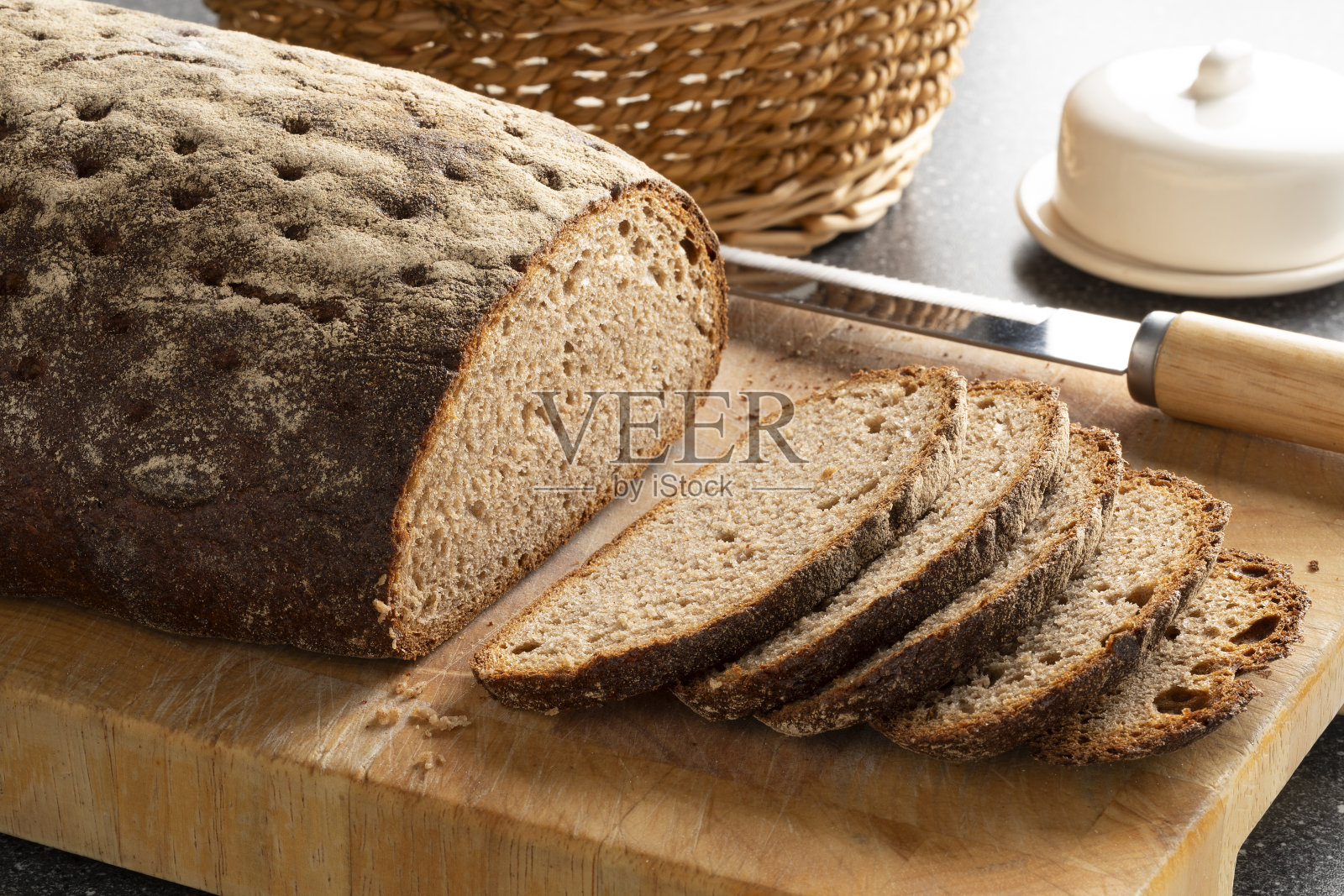 将经典的酵母混合黑麦面包切成薄片，放在砧板上照片摄影图片