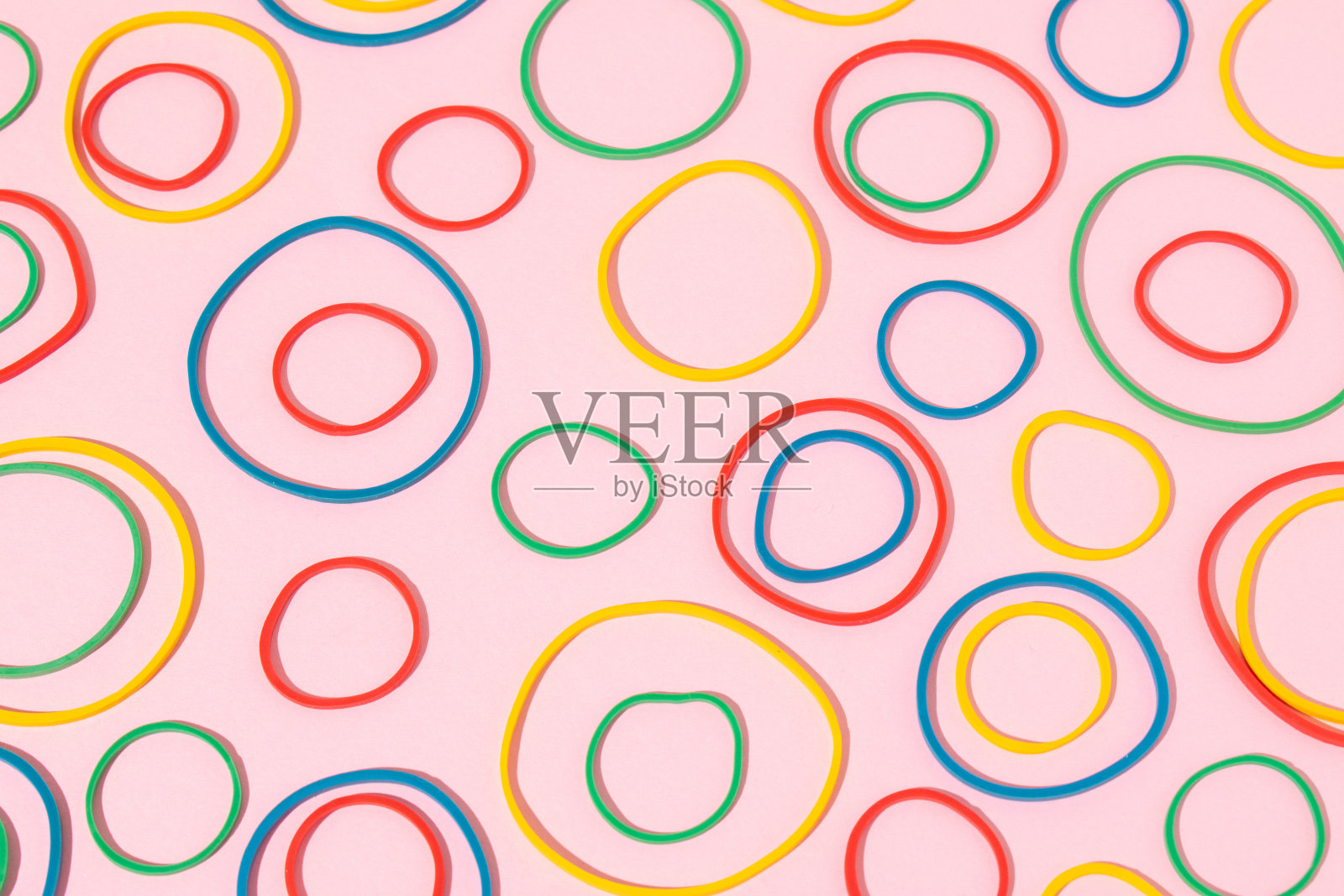 多色橡皮筋排列在明亮的粉红色背景上。夏天的颜色背景。照片摄影图片