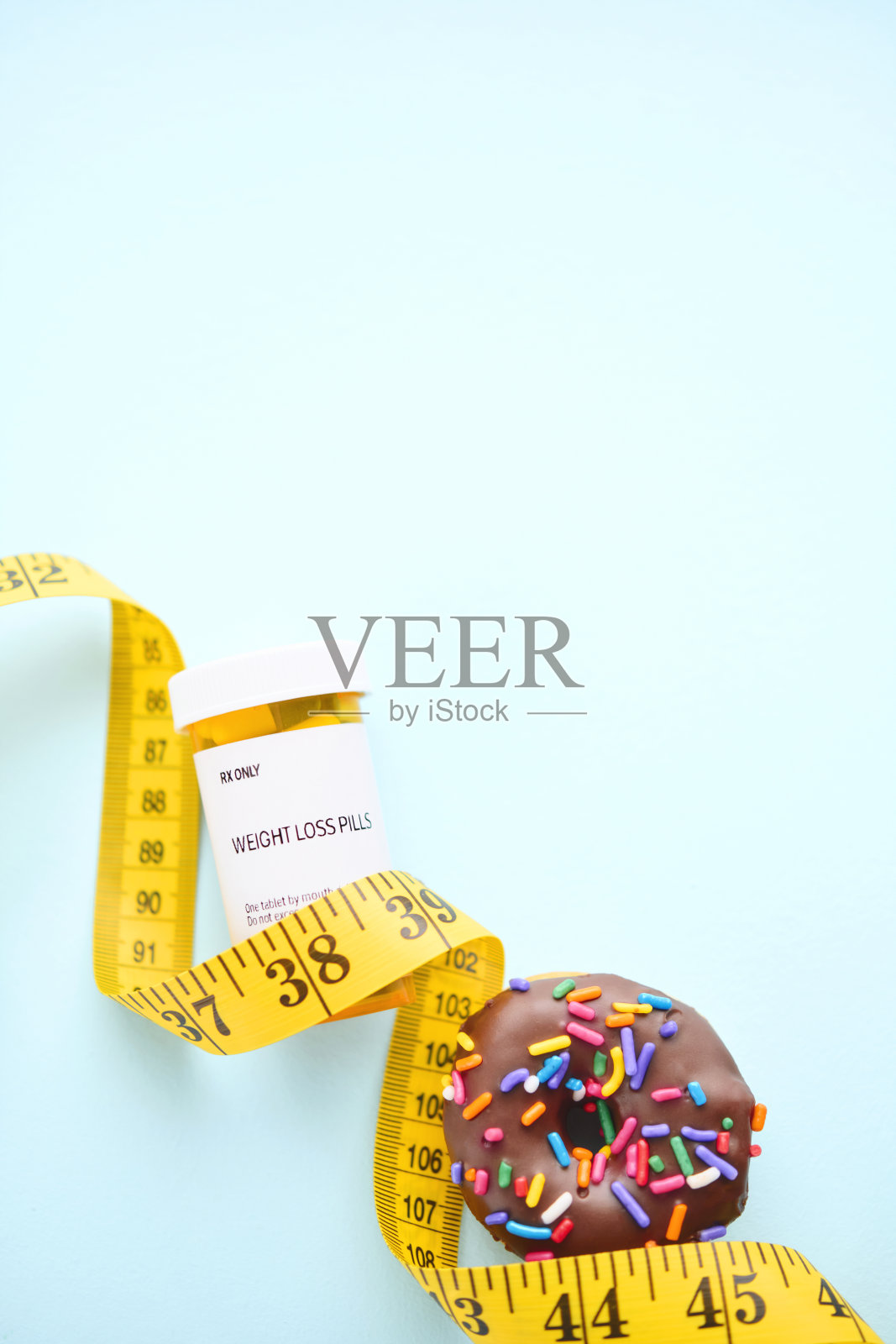 一个甜甜圈，还有减肥药和卷尺照片摄影图片