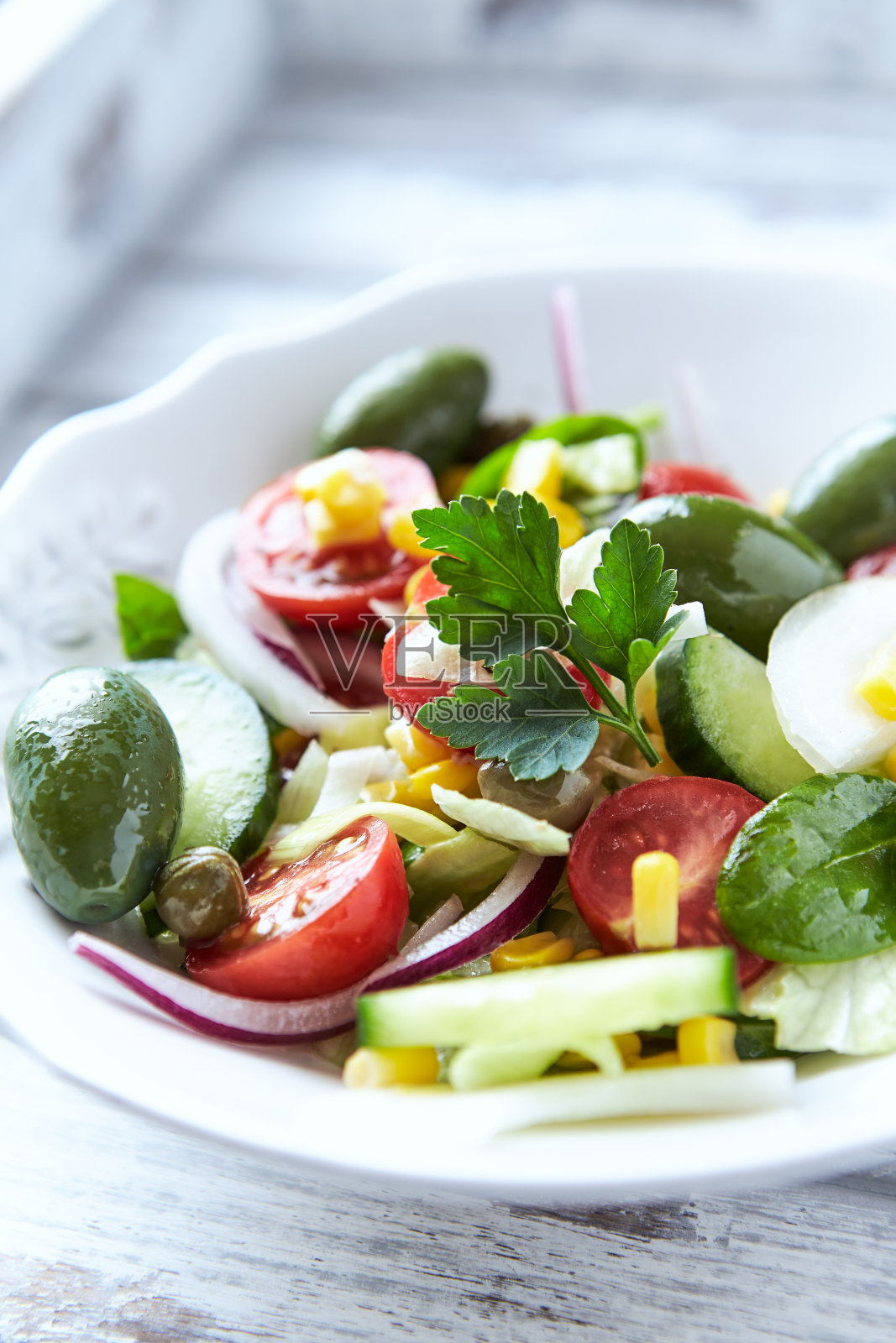 简单的绿橄榄，黄瓜和圣女果沙拉。明亮的木制背景。照片摄影图片