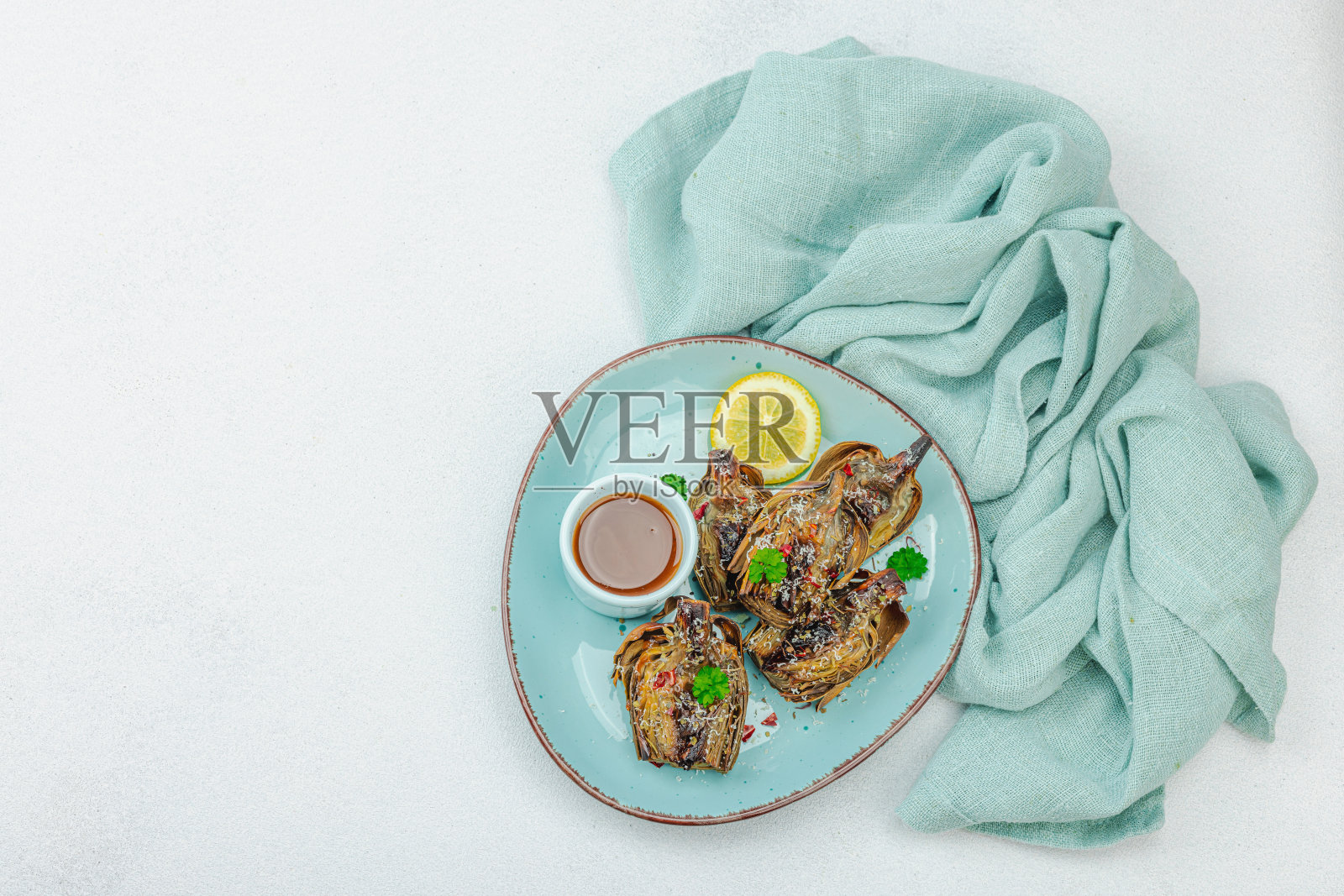 美味的烤洋蓟配帕尔马干酪和酱汁。橄榄油，大蒜，欧芹和柠檬照片摄影图片