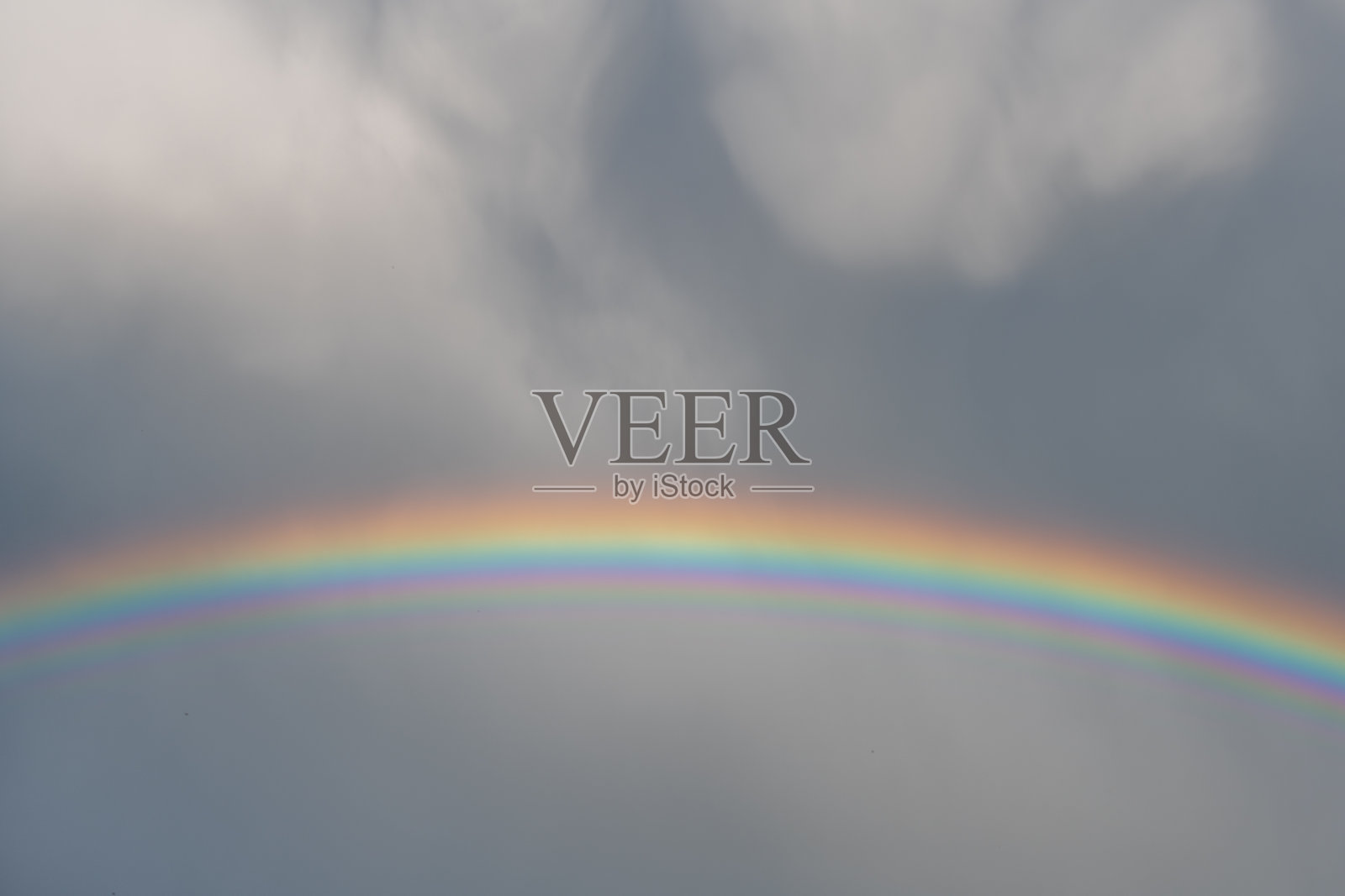 春天雨云中出现彩虹。照片摄影图片