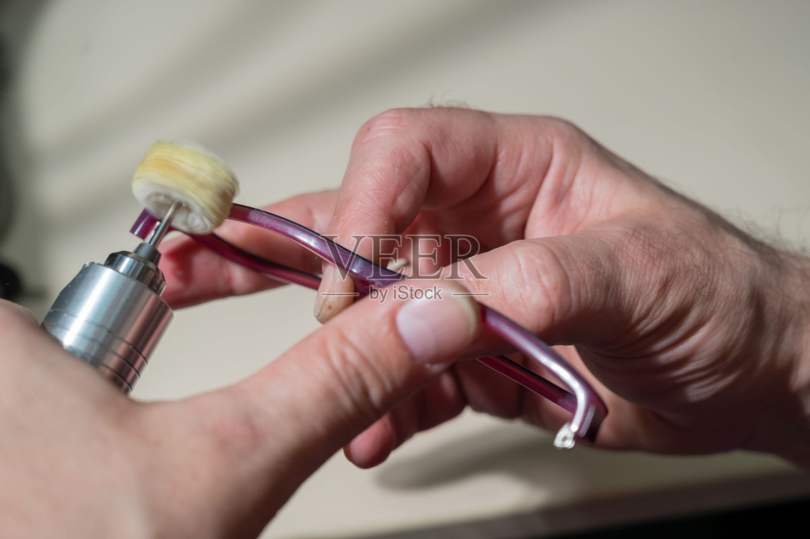 一位配镜技师在打磨眼镜框。专业的配镜师修理眼镜。照片摄影图片