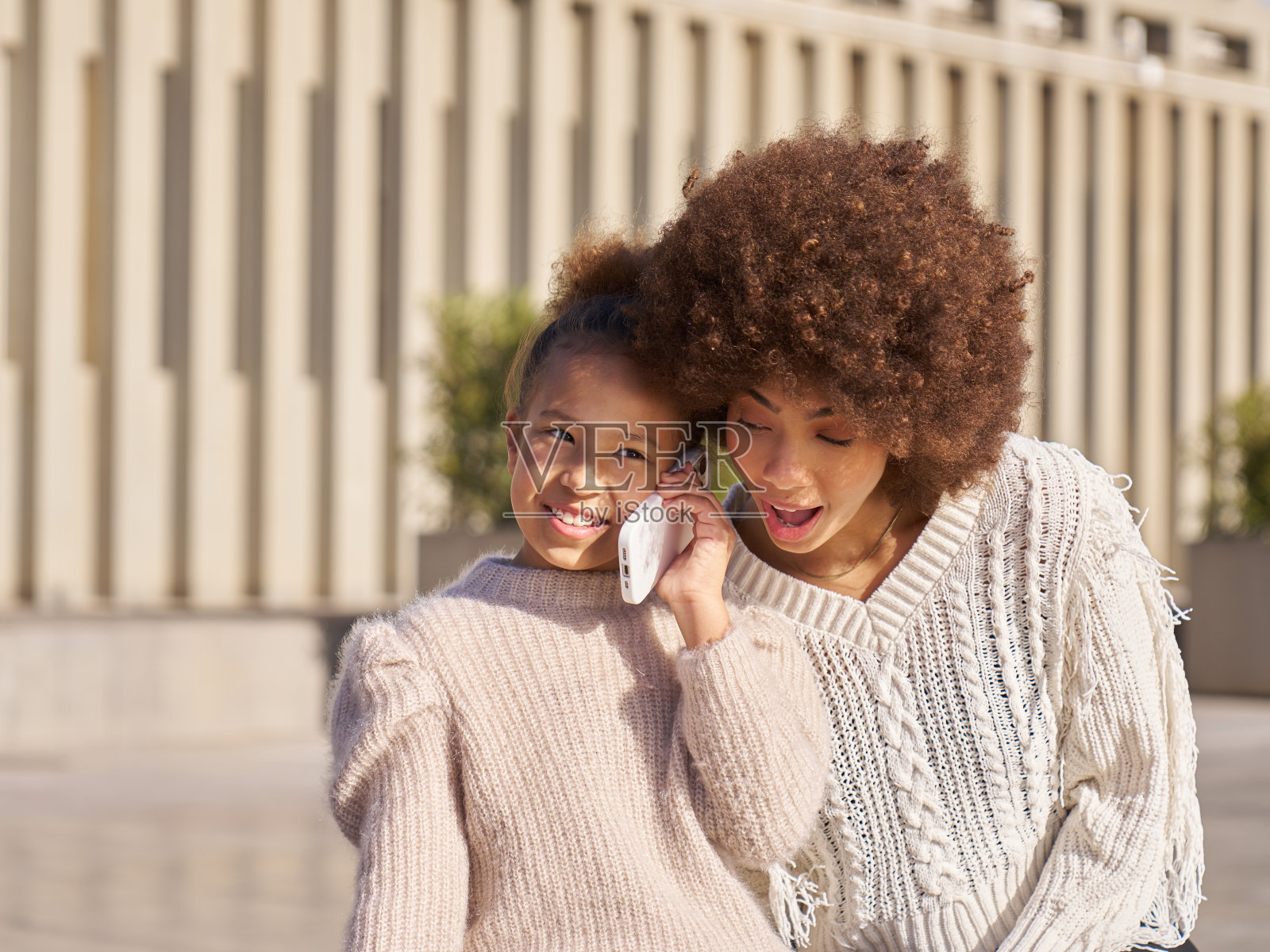 一个小女孩和她姐姐坐在长凳上照片摄影图片