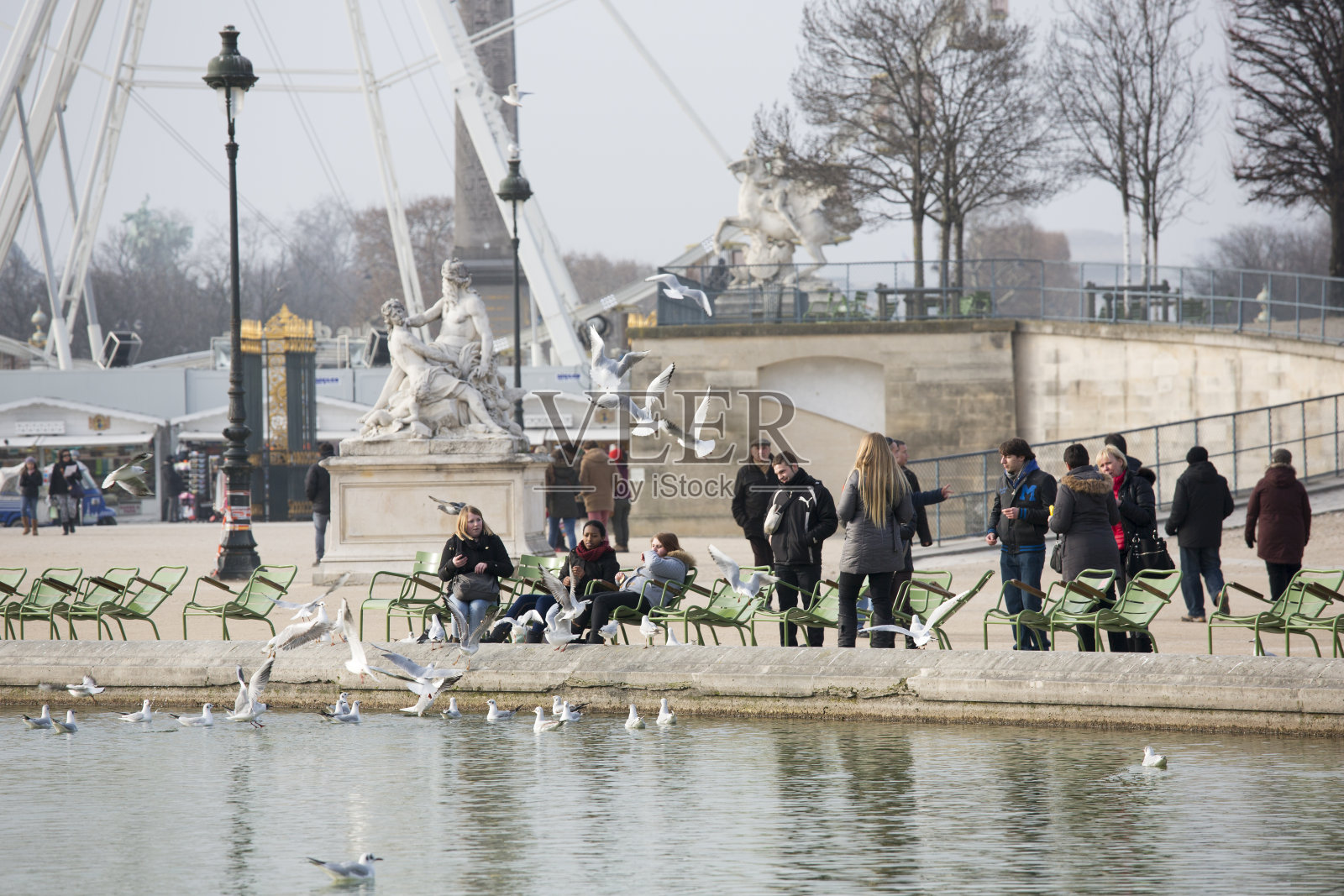 法国巴黎杜伊勒里花园的妇女喂鸽子照片摄影图片