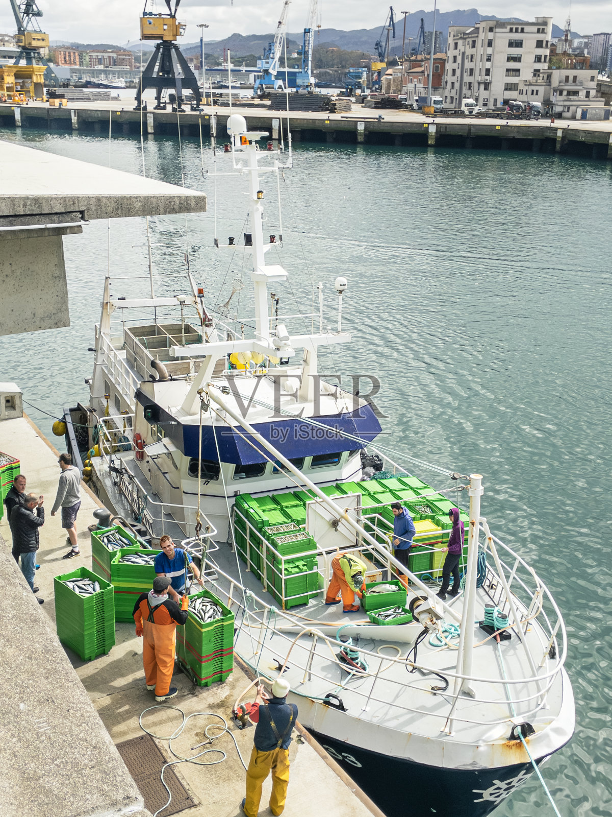 一艘传统的沿海渔船在抵达风景如画的帕萨伊斯港口后卸载新捕获的鱼。西班牙。照片摄影图片