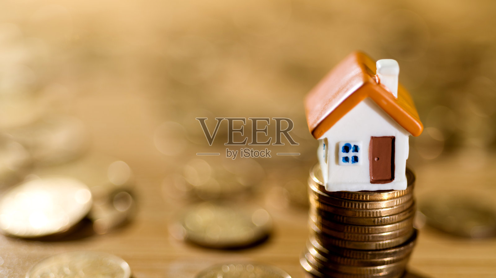 房子模型在硬币堆的顶部照片摄影图片