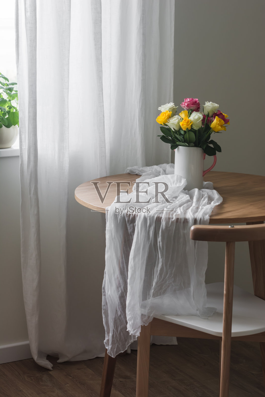 美学装饰——客厅里的木桌上铺着细布桌布，陶瓷花瓶里插着一束玫瑰照片摄影图片