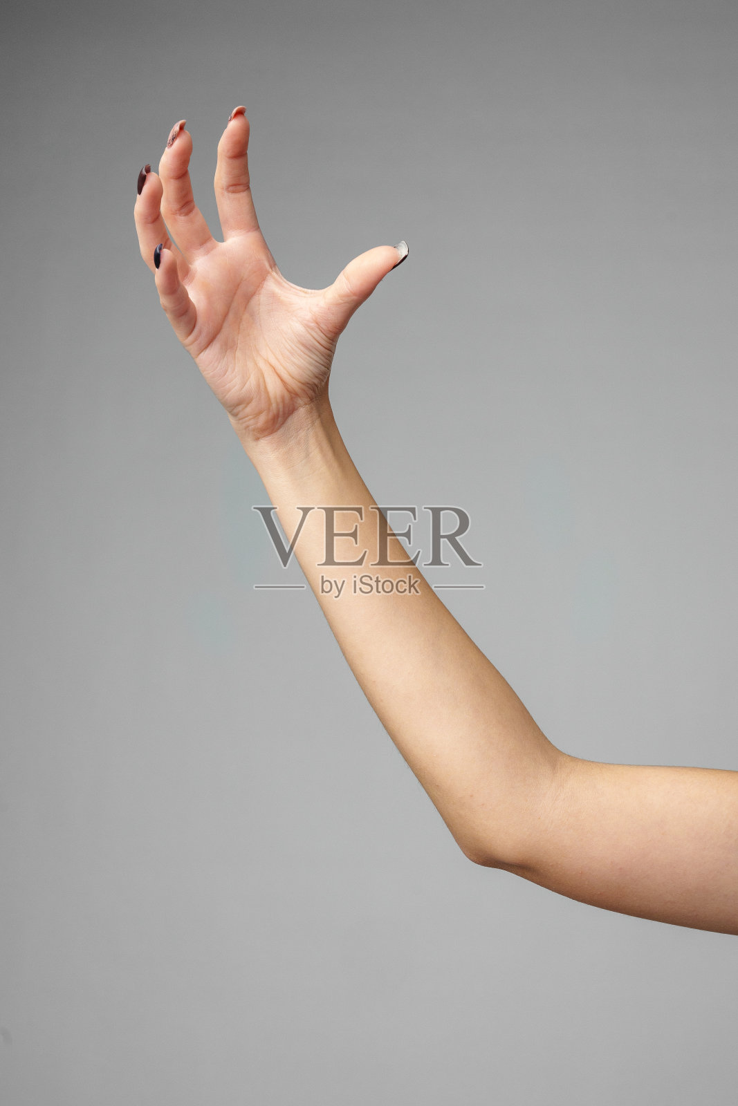 在灰色背景下，伸出的的手臂和放松的手照片摄影图片