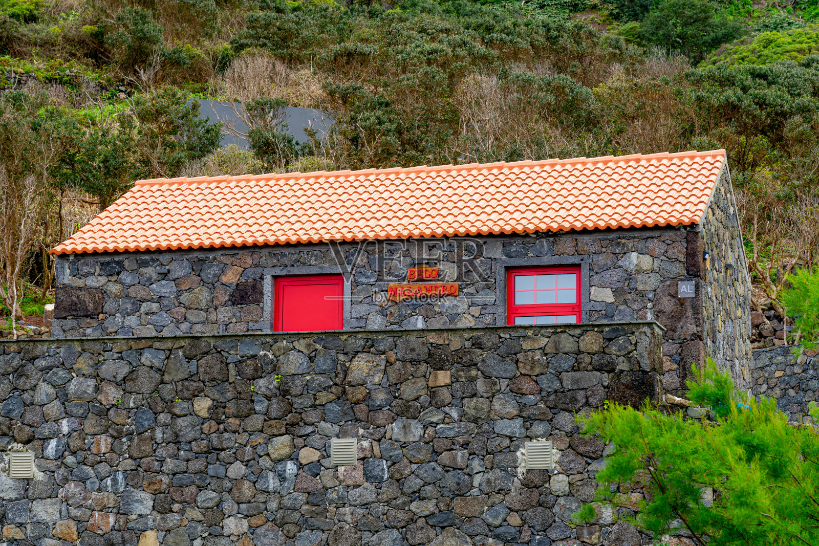 黑色的石头房子，高对比度的红色门窗，宽扎当地的住宿位于fajã do下面。照片摄影图片