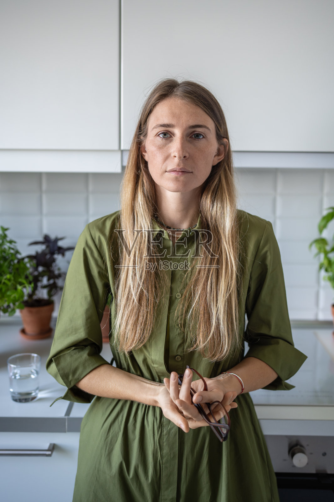 疲惫的金发中年妇女肖像，手持眼镜平静地看着镜头照片摄影图片