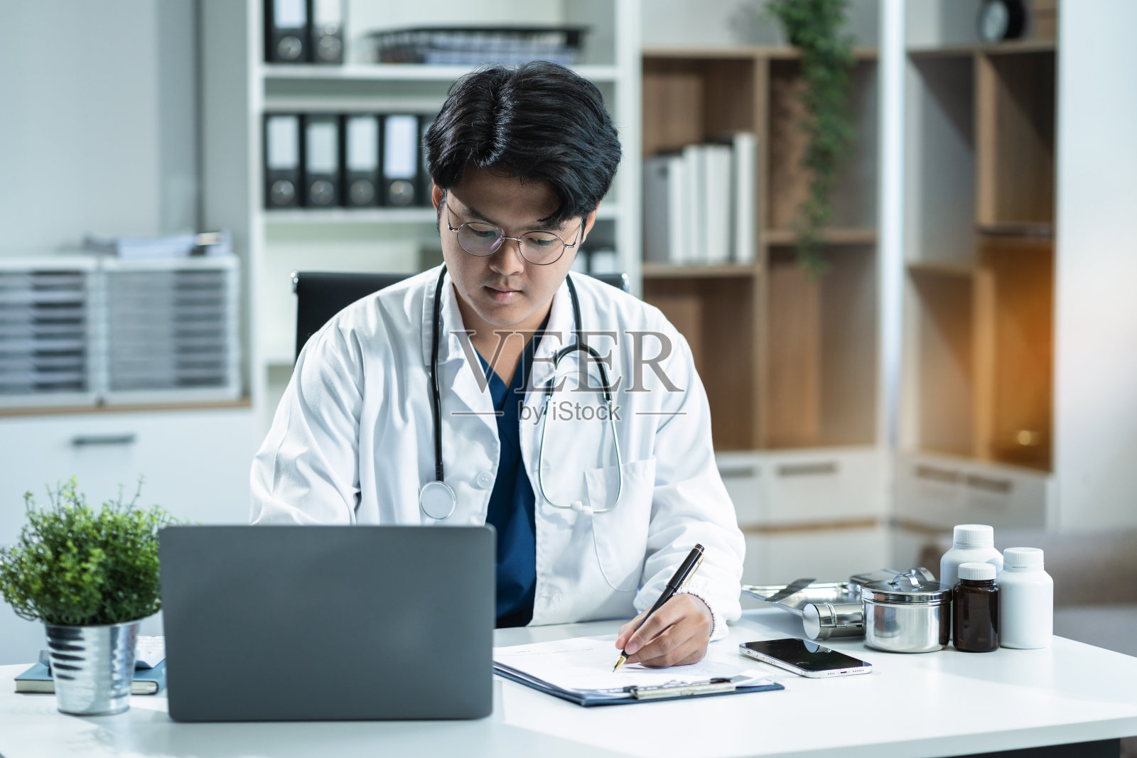 医疗技术概念，早晨，在一间现代化办公室的办公桌前，医生正在摆弄一台数字平板电脑。照片摄影图片