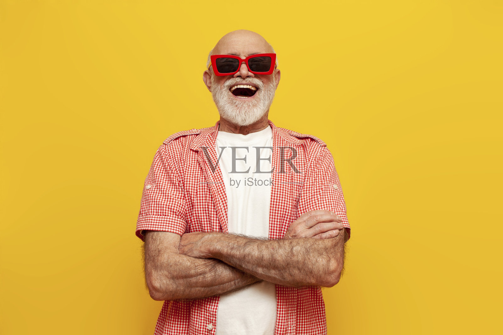 在黄色孤立的背景上，穿着夏日衬衫、戴着墨镜的老祖父张着嘴欢呼雀跃照片摄影图片