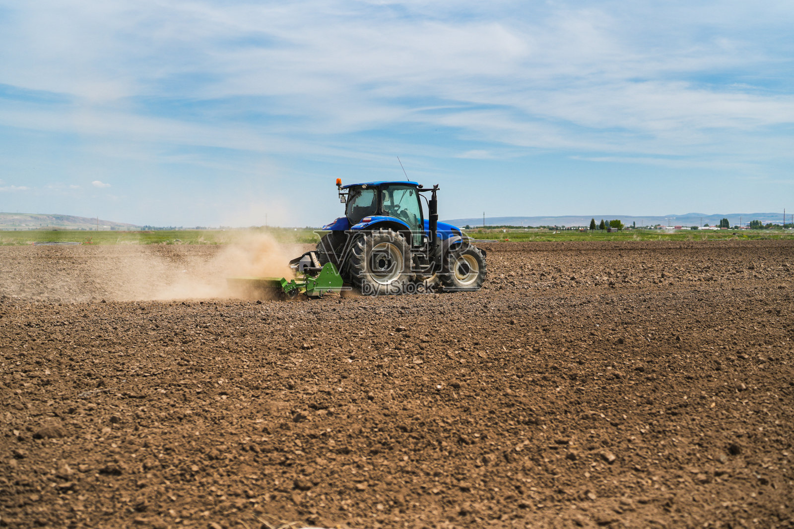农民用拖拉机和旋耕机在农用地上耕地照片摄影图片