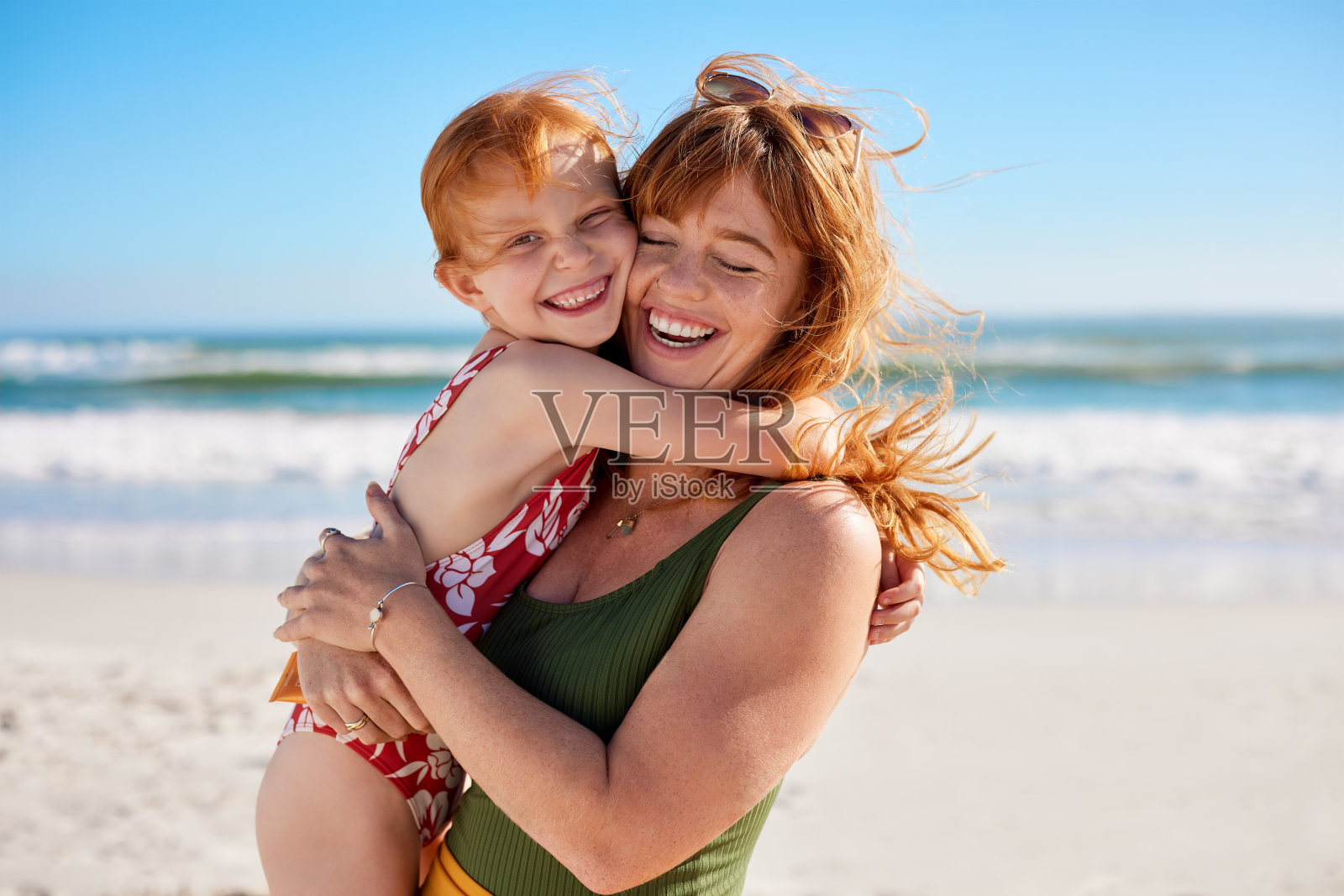 红头发的妈妈和女儿在沙滩上拥抱着玩耍照片摄影图片