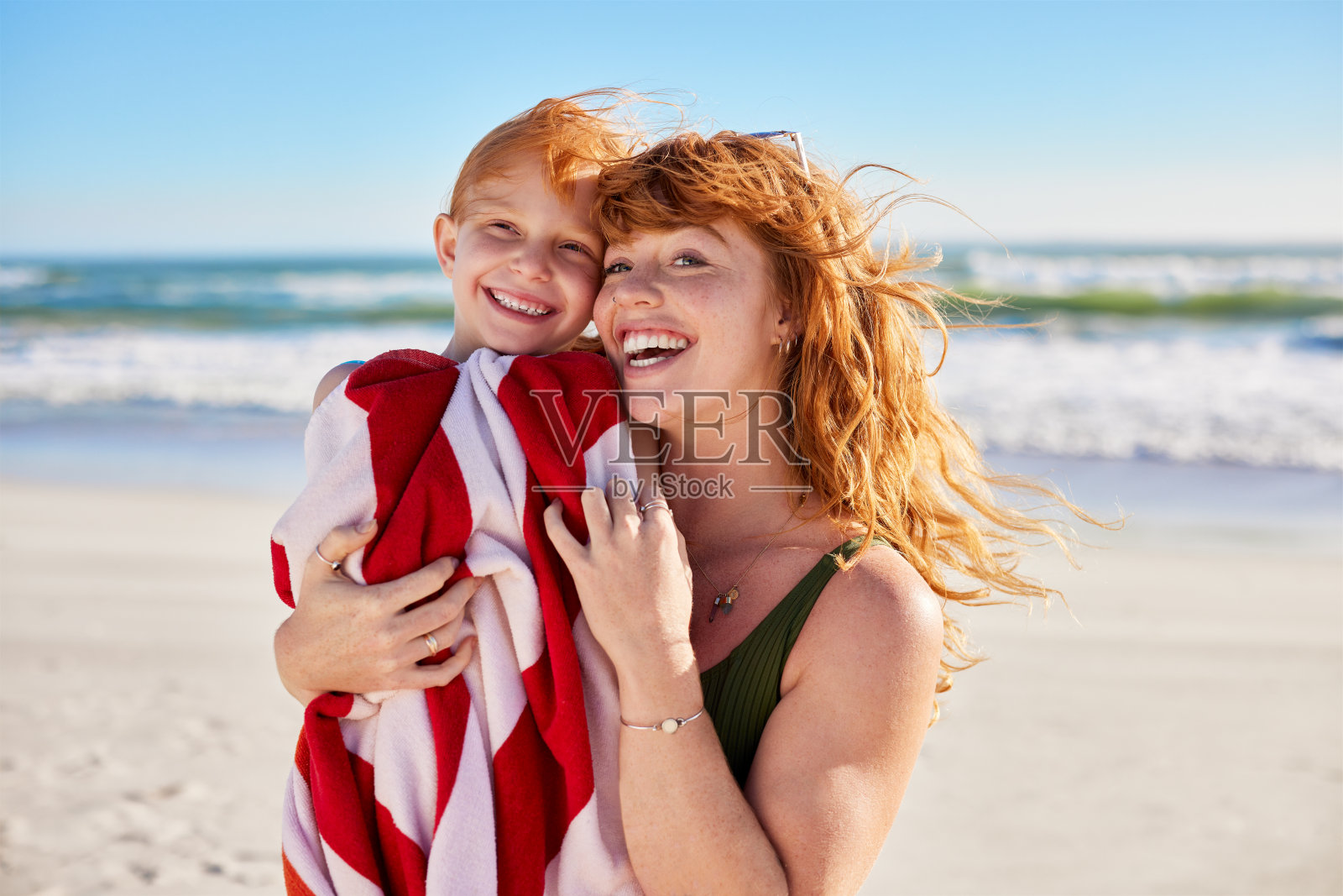 可爱的女人在沙滩上微笑着用毛巾抱着孩子照片摄影图片