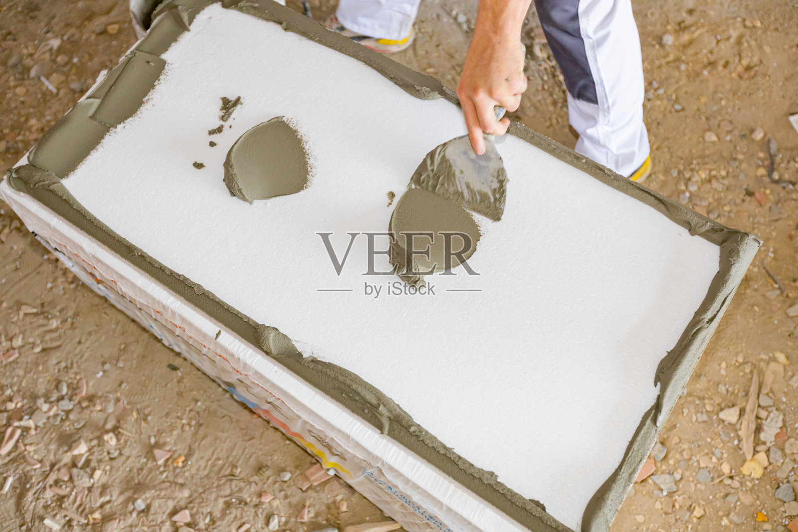 工人用抹刀将胶水涂在隔热材料、泡沫塑料上照片摄影图片