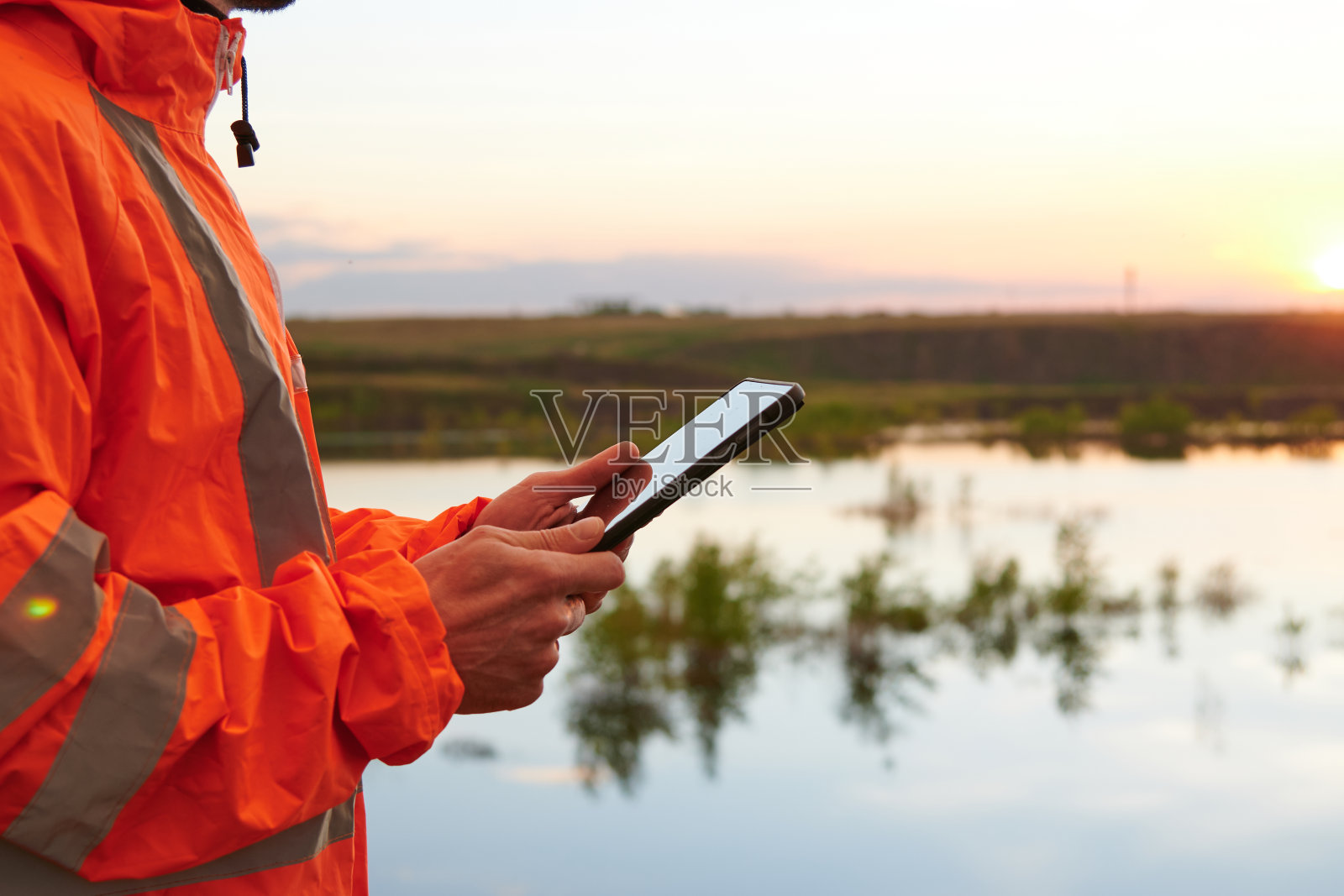 一个穿着雨衣拿着平板电脑的工程师照片摄影图片