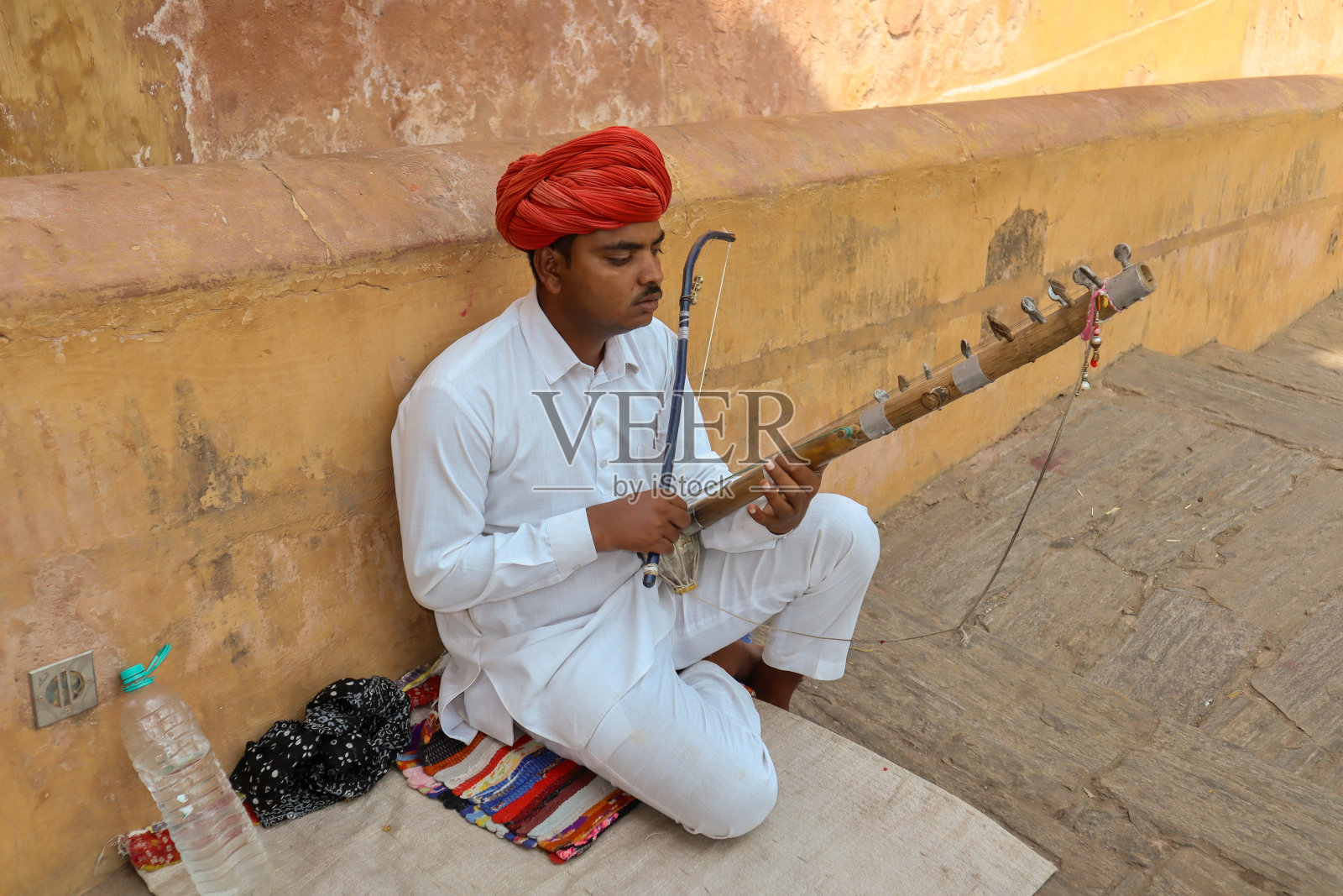 在印度拉贾斯坦邦斋浦尔,一位年轻的民间音乐家在琥珀堡宫殿的台阶上演奏着当地的弦乐器“Ravan Hatta”。照片摄影图片