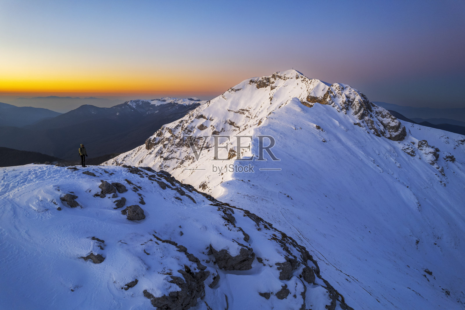 徒步旅行者欣赏黄昏时被雪覆盖的山峰，亚平宁山脉，意大利照片摄影图片