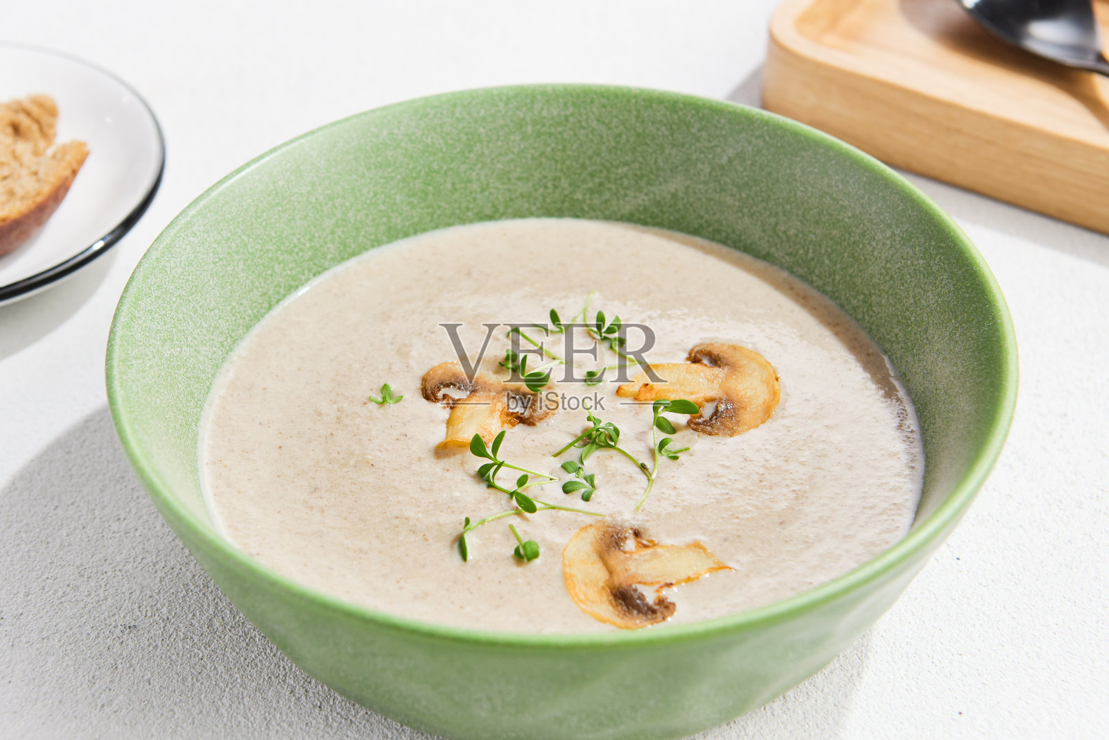 奶油蘑菇泥汤配以新鲜香草点缀在绿色的碗在浅色背景照片摄影图片