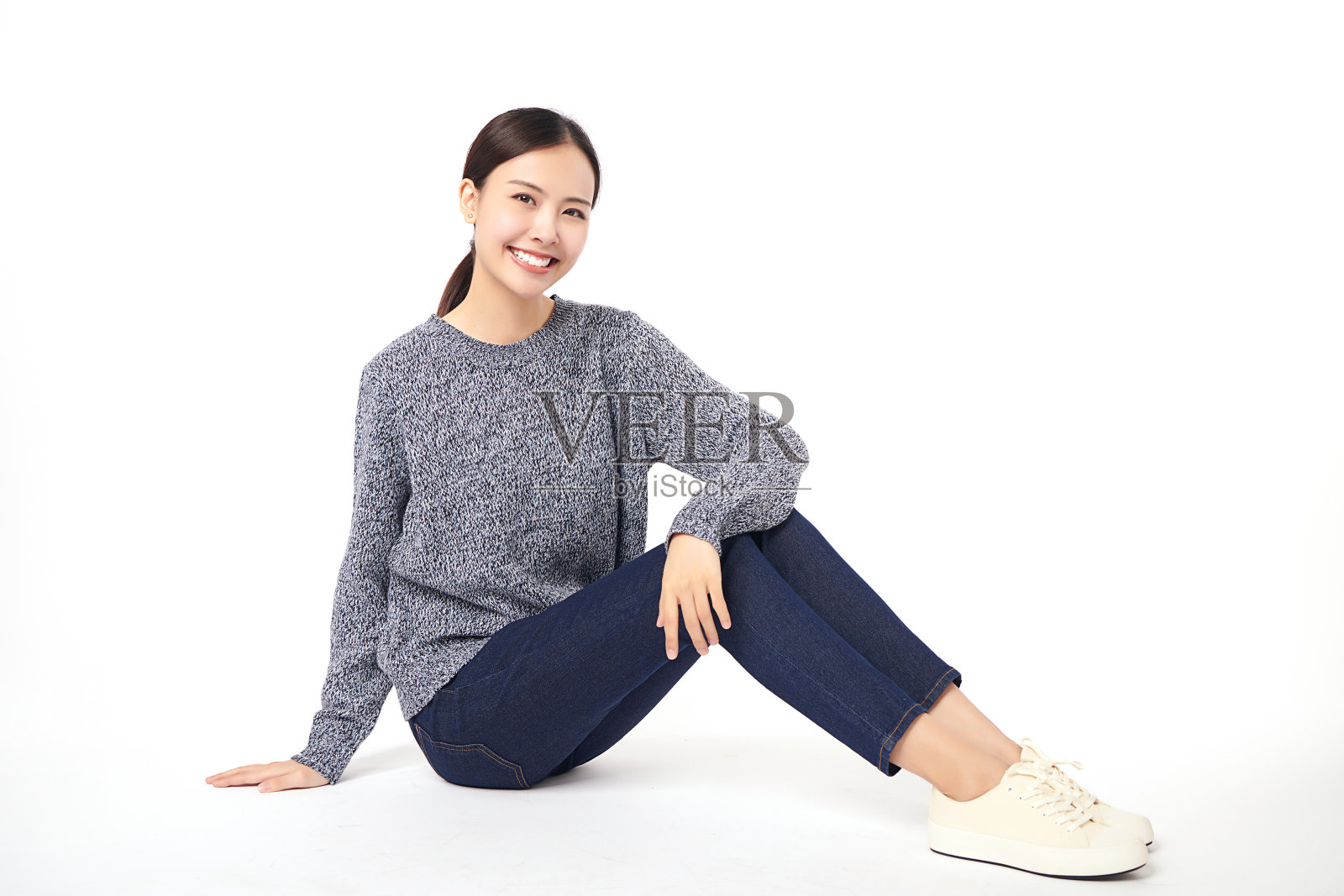 美丽的年轻亚洲女子微笑着快乐地坐在白色背景的地板上，年轻的女女孩带着完美的微笑。照片摄影图片