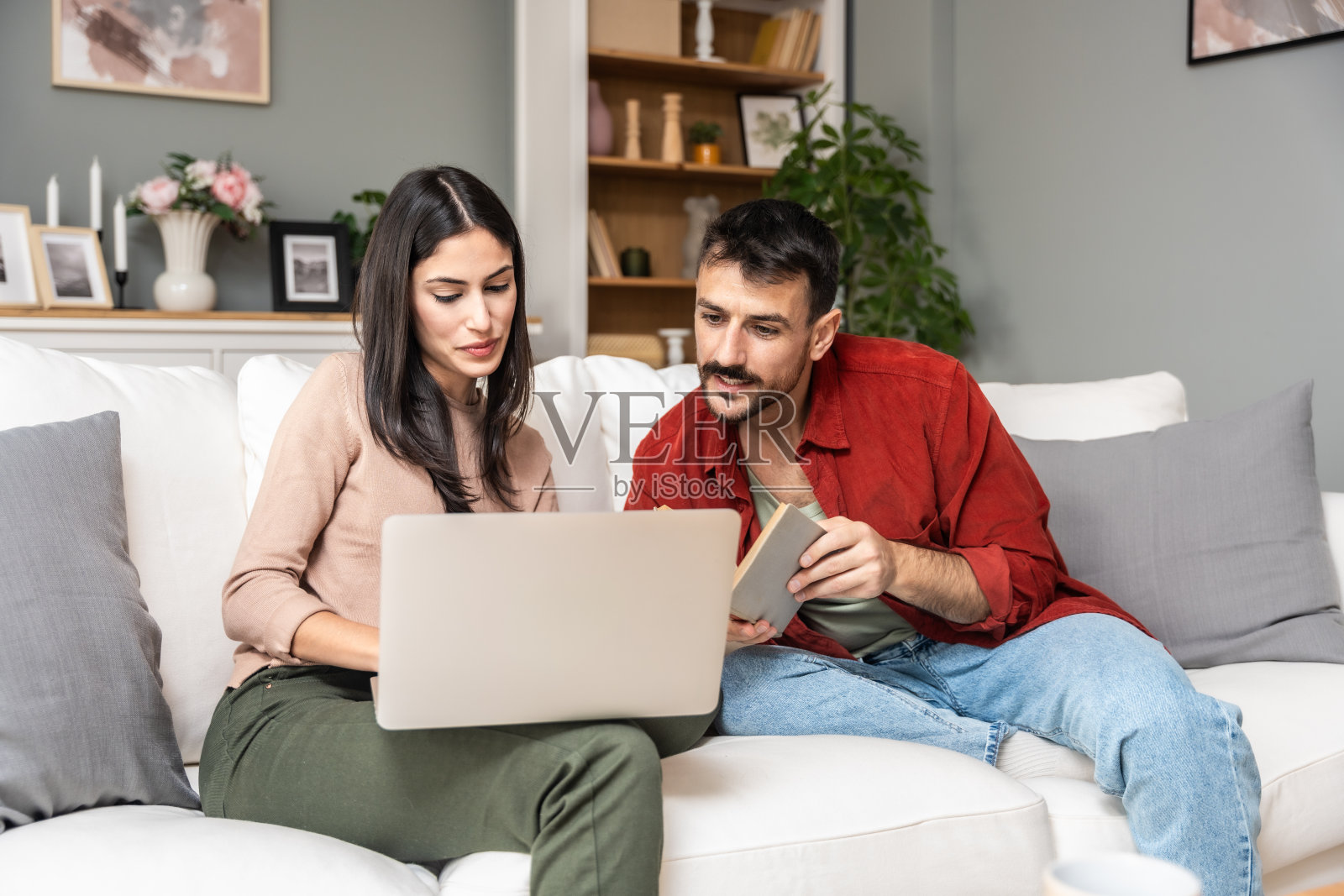 简单的生活。幸福的年轻夫妇夫妇放松地坐在客厅的沙发上看书，一起喝茶，上网，平静的生活方式夫妇爱书的人在家里休息享受生活照片摄影图片