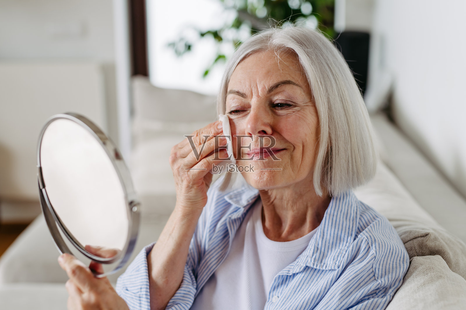 适合成熟的女性的护肤品。美丽的老妇人的画像，头发花白，清洁，照顾她的皮肤。照片摄影图片