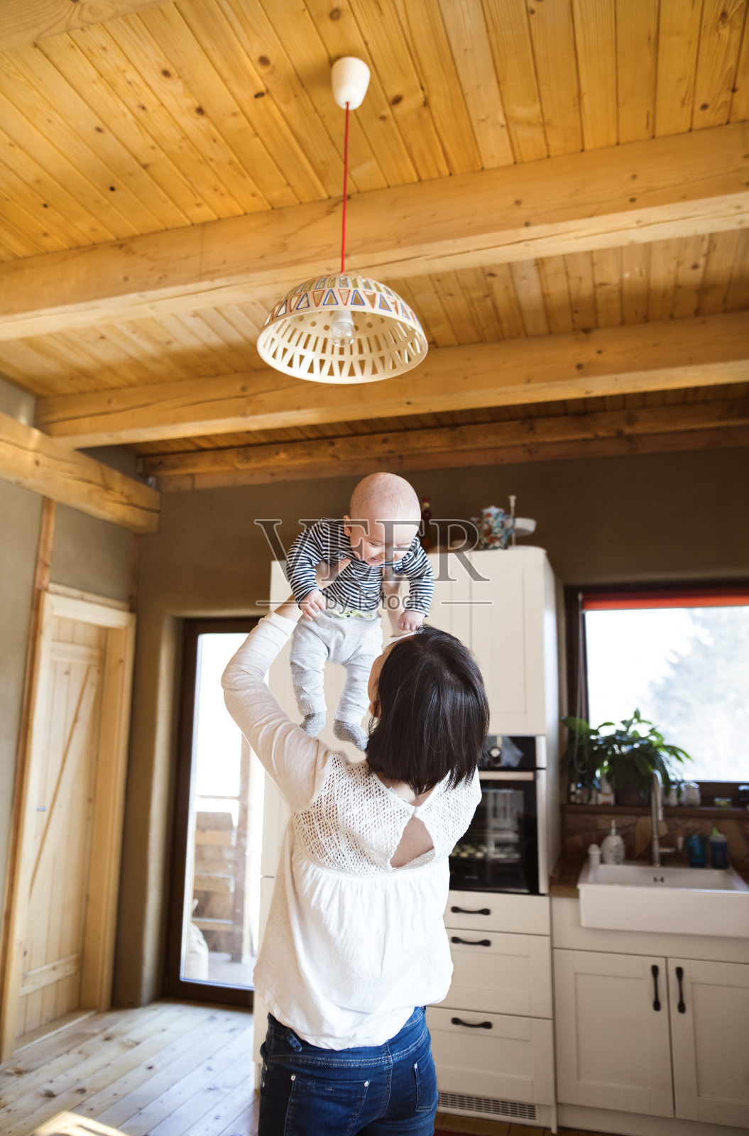 妈妈抱着小婴儿在空中玩耍。无条件的父爱，母亲节的概念。照片摄影图片