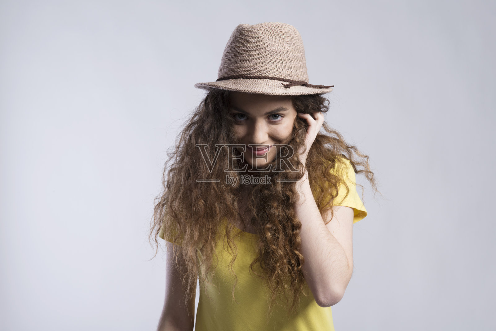 一个漂亮的少女的肖像，卷发，戴着帽子。工作室拍摄，白色背景与复制空间照片摄影图片