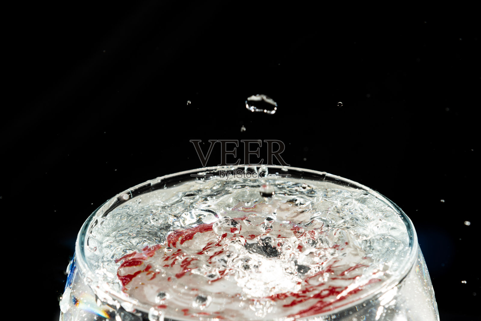 一个透明玻璃杯的特写，里面有水，水滴飞溅。照片摄影图片