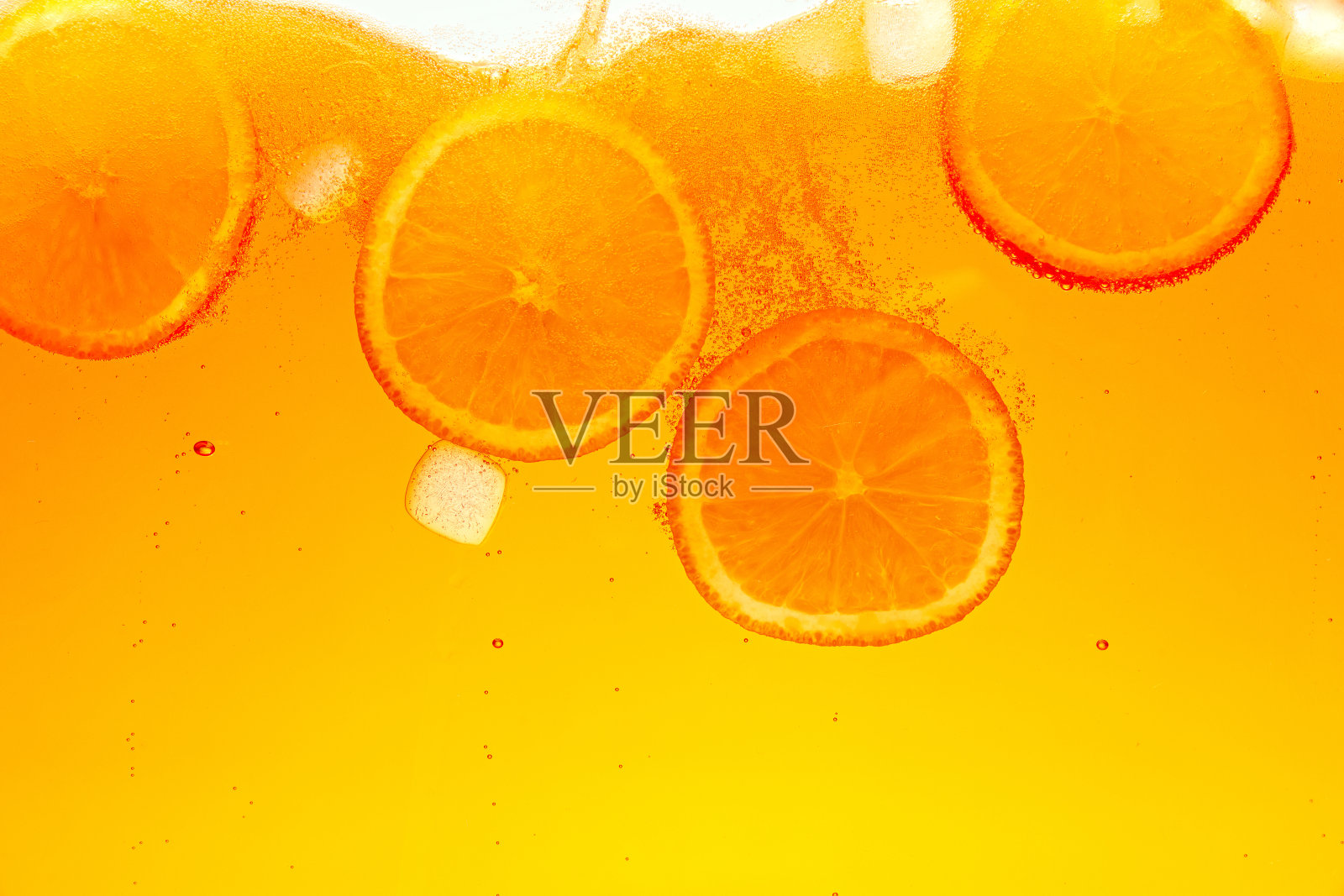 变形的照片。在气泡饮料中，有趣的气泡围绕着饱满的橘子片。抽象的壁纸。照片摄影图片