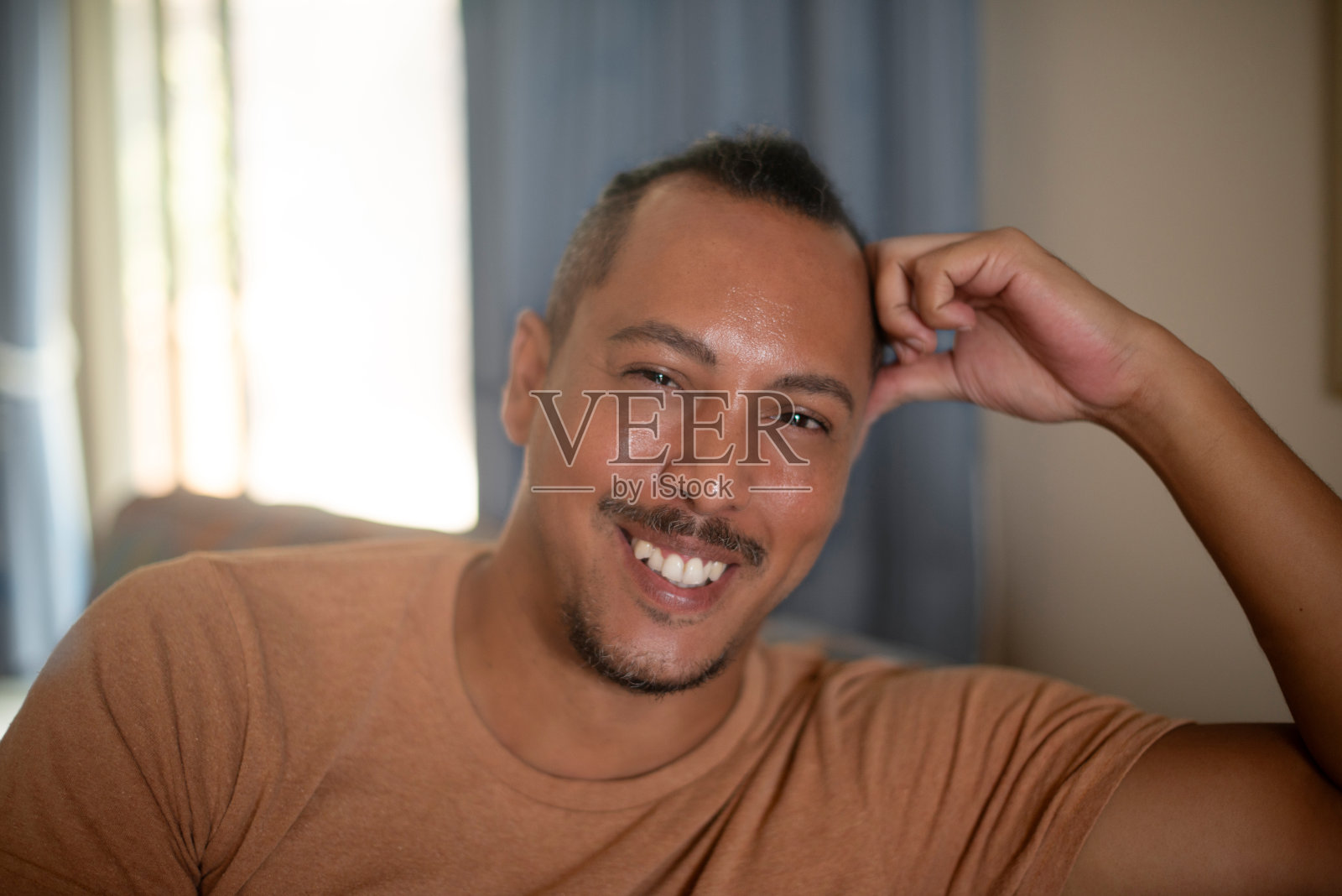 微笑，休息和客厅沙发上的男人肖像，积极，良好和自信的态度。周末在现代公寓或家中，一个快乐、平静的男性在沙发上休息。照片摄影图片