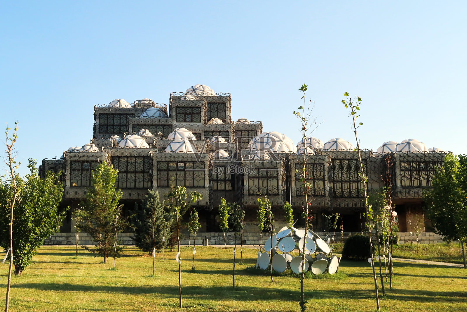 科索沃国立大学图书馆,覆盖着金属网格,网,许多顶部有几何图案的白色圆顶,是科索沃普里什蒂纳市中心的社会主义,野兽派建筑的一个例子照片摄影图片