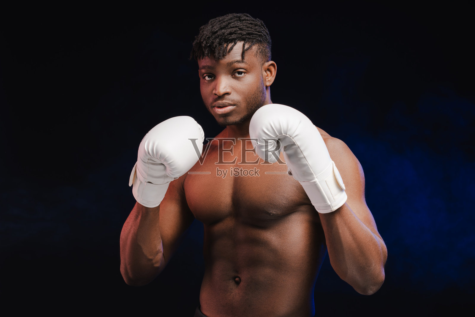 年轻迷人的非裔美国男性拳击手赤裸上身，肌肉发达，戴着白手套照片摄影图片