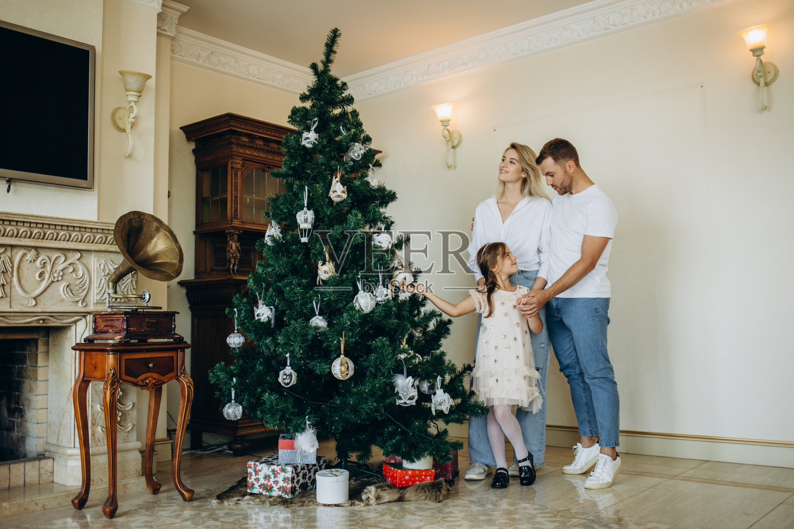 幸福的一家人在家里圣诞树旁戴着圣诞老人的帽子照片摄影图片