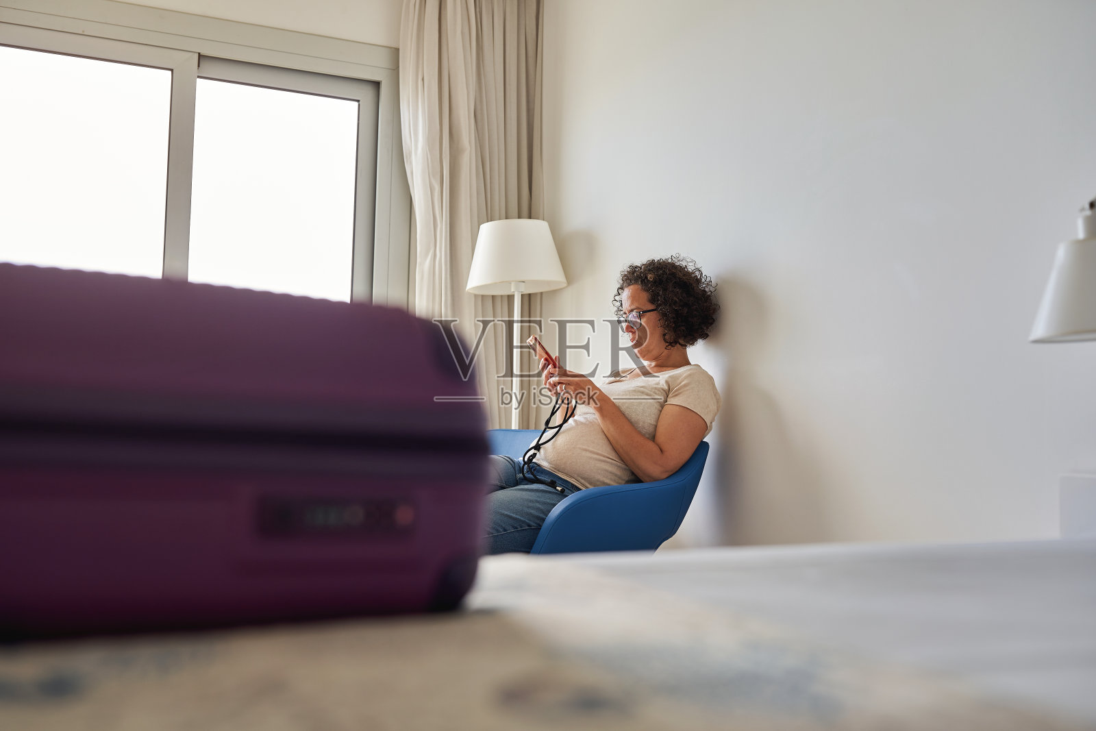 一位女士在酒店房间里看智能手机。照片摄影图片